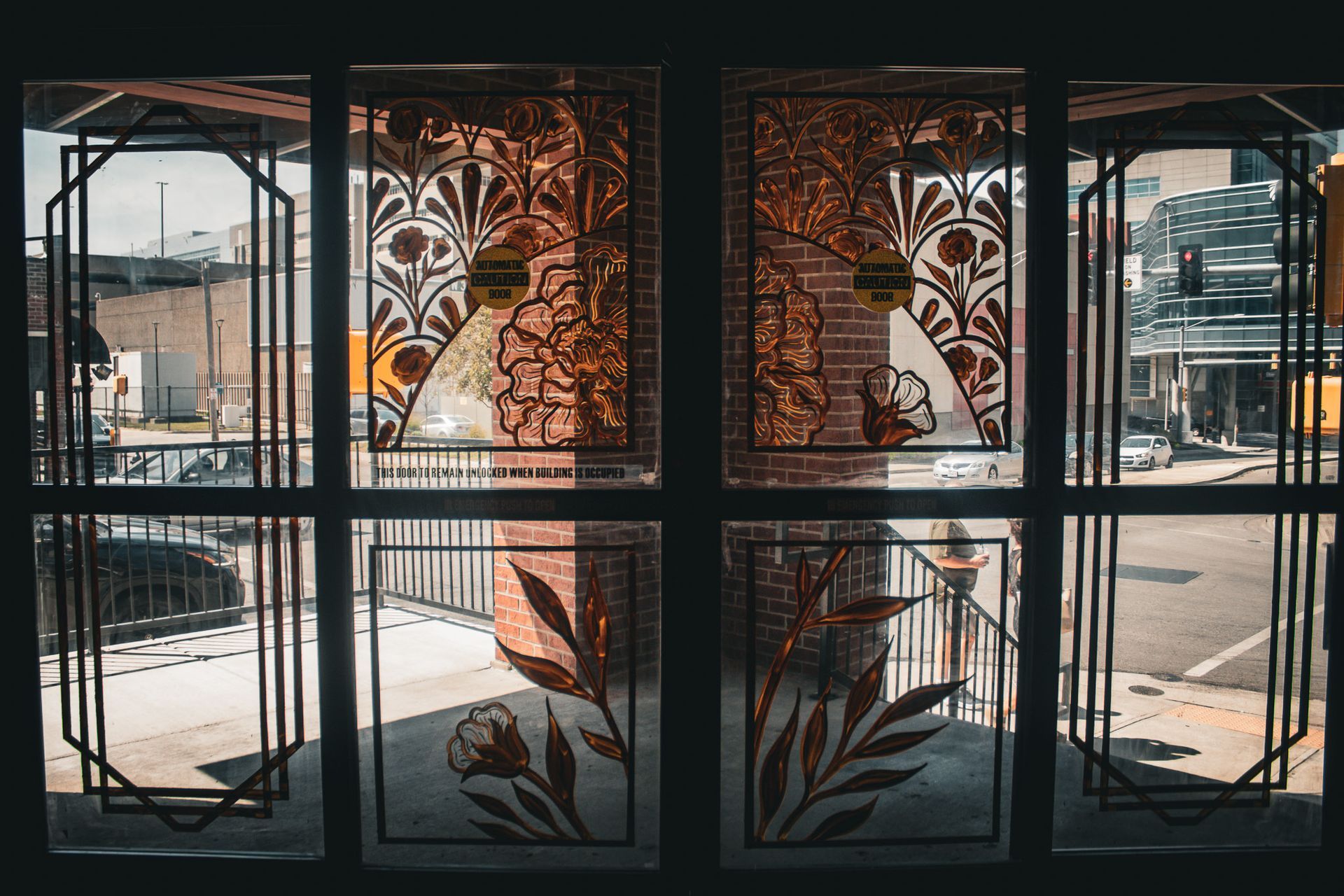 Decorative glass windows with floral patterns and a sunlit outdoor view beyond