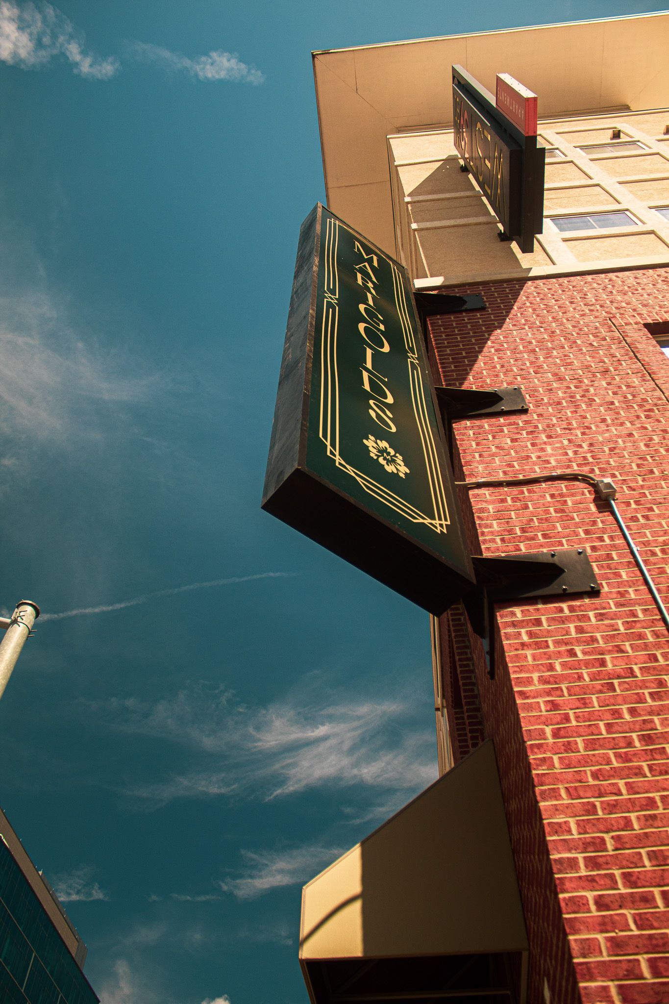 Green “Latin” sign on a brick building against a blue sky