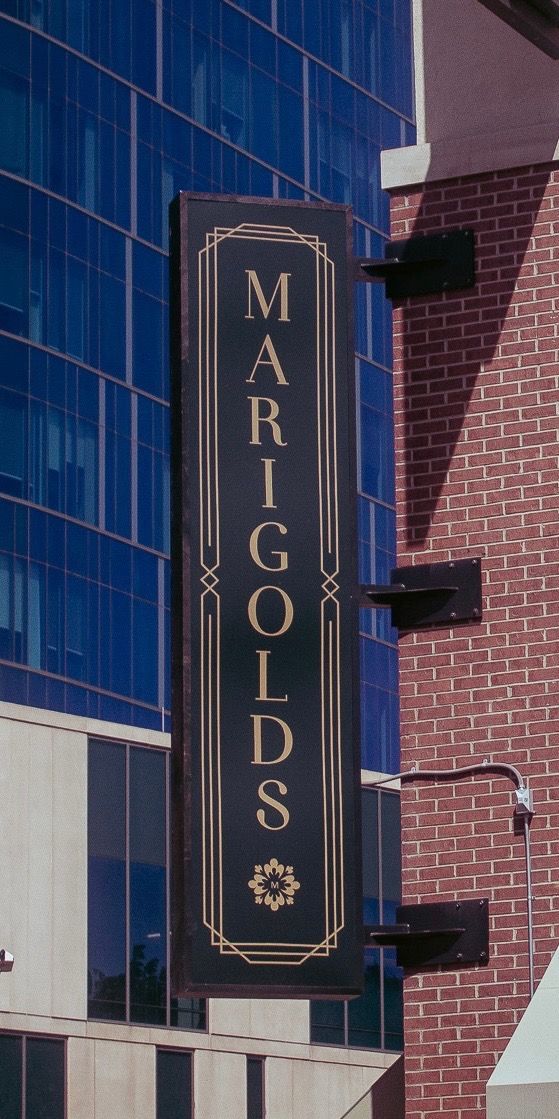 Brick storefront entrance on a city street, with a vertical sign and nearby crosswalk markings.