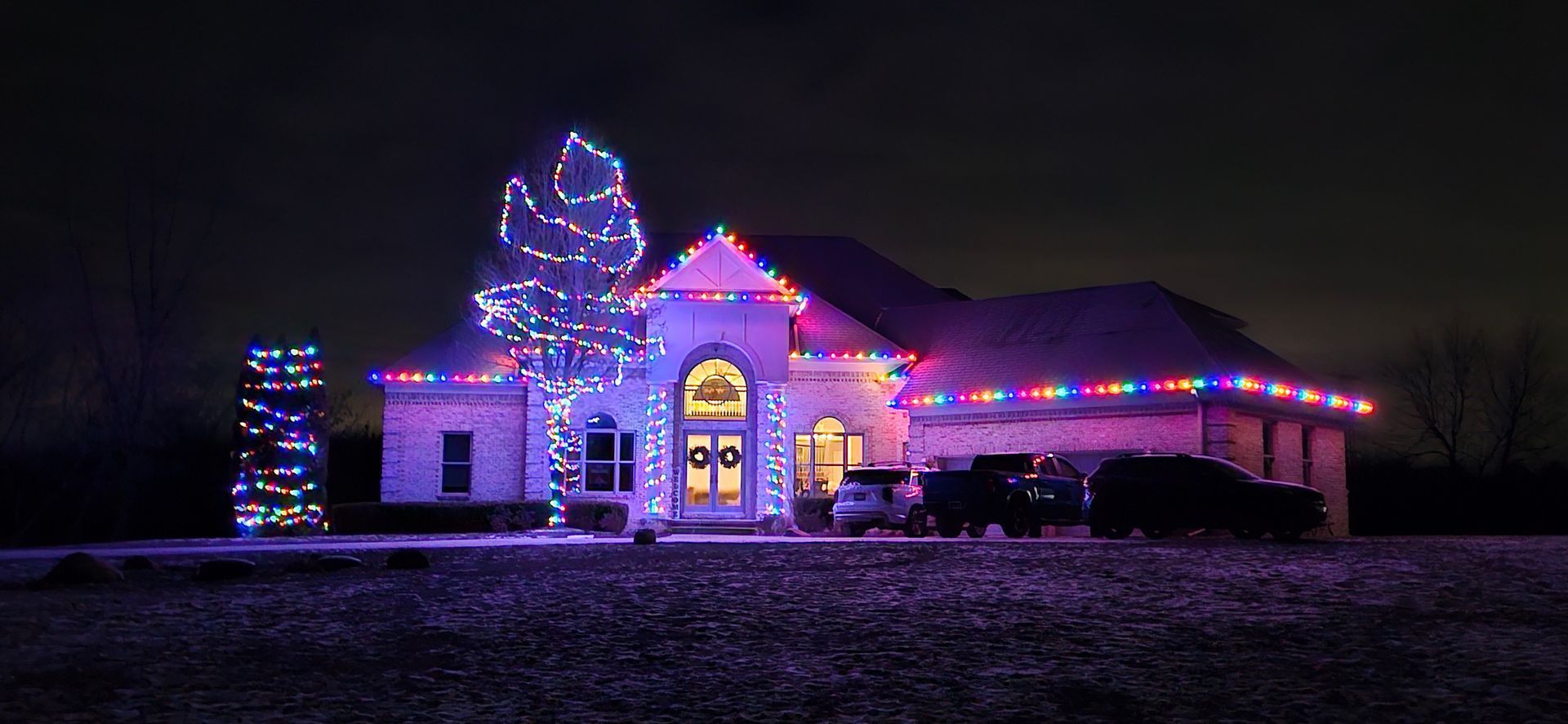 House and yard decorated with colorful Christmas lights at night