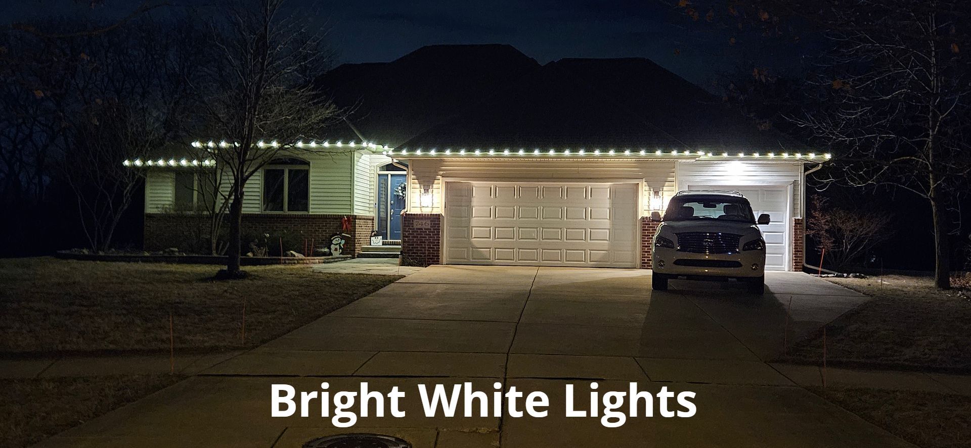 Nighttime house with bright white lights outlining the garage and roof, SUV parked in driveway
