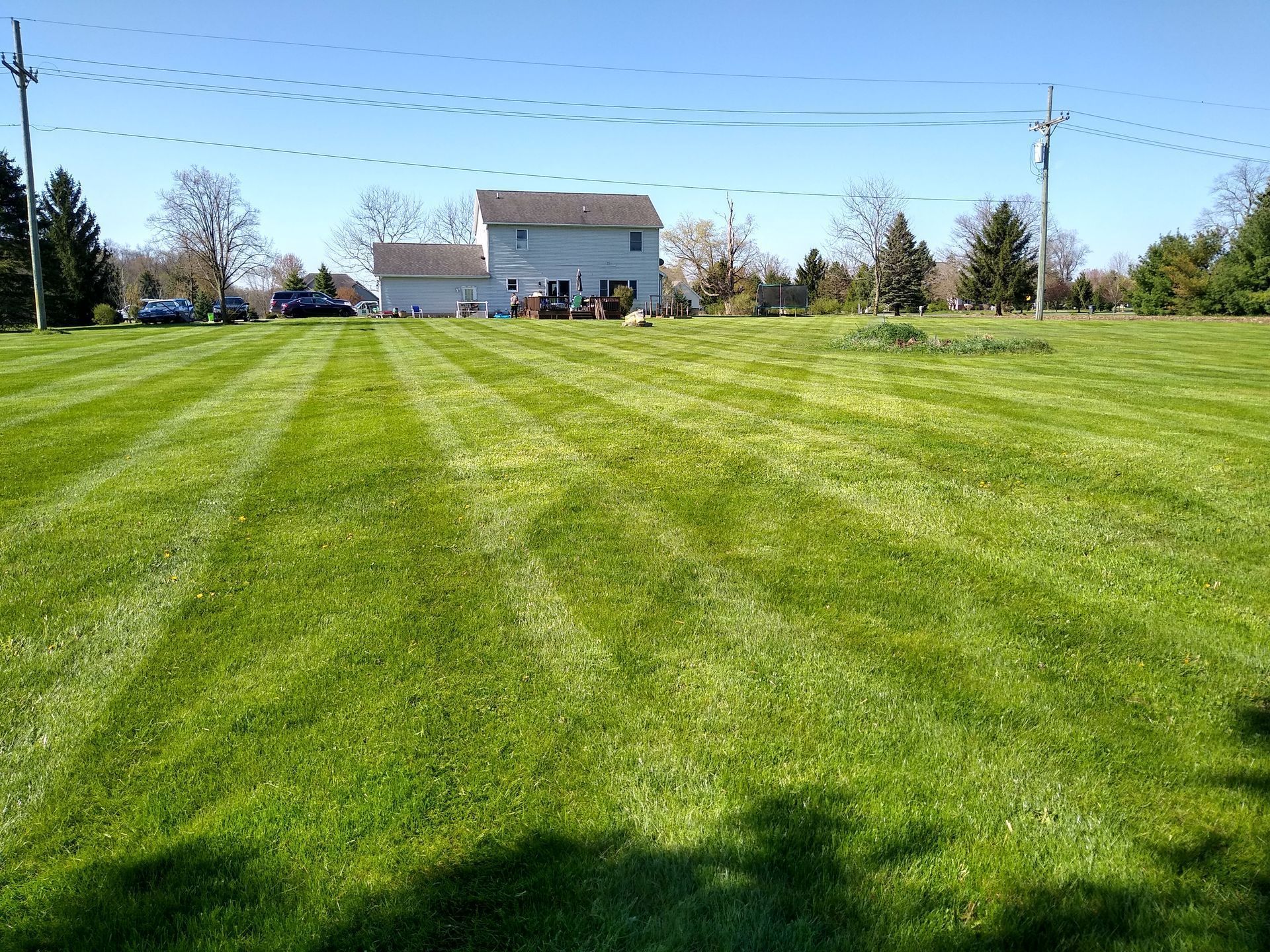 Wide grassy field leading to a white building on a sunny day, with a few people near the entrance