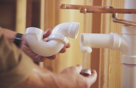 Hands of plumber assembling pvc pipes