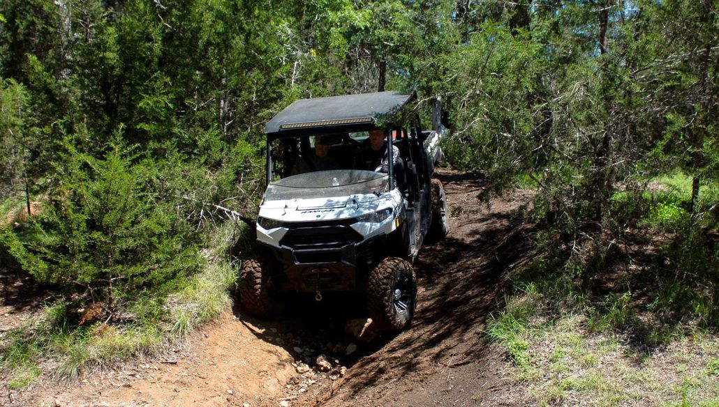 Off-road utility vehicle driving through a muddy forest trail