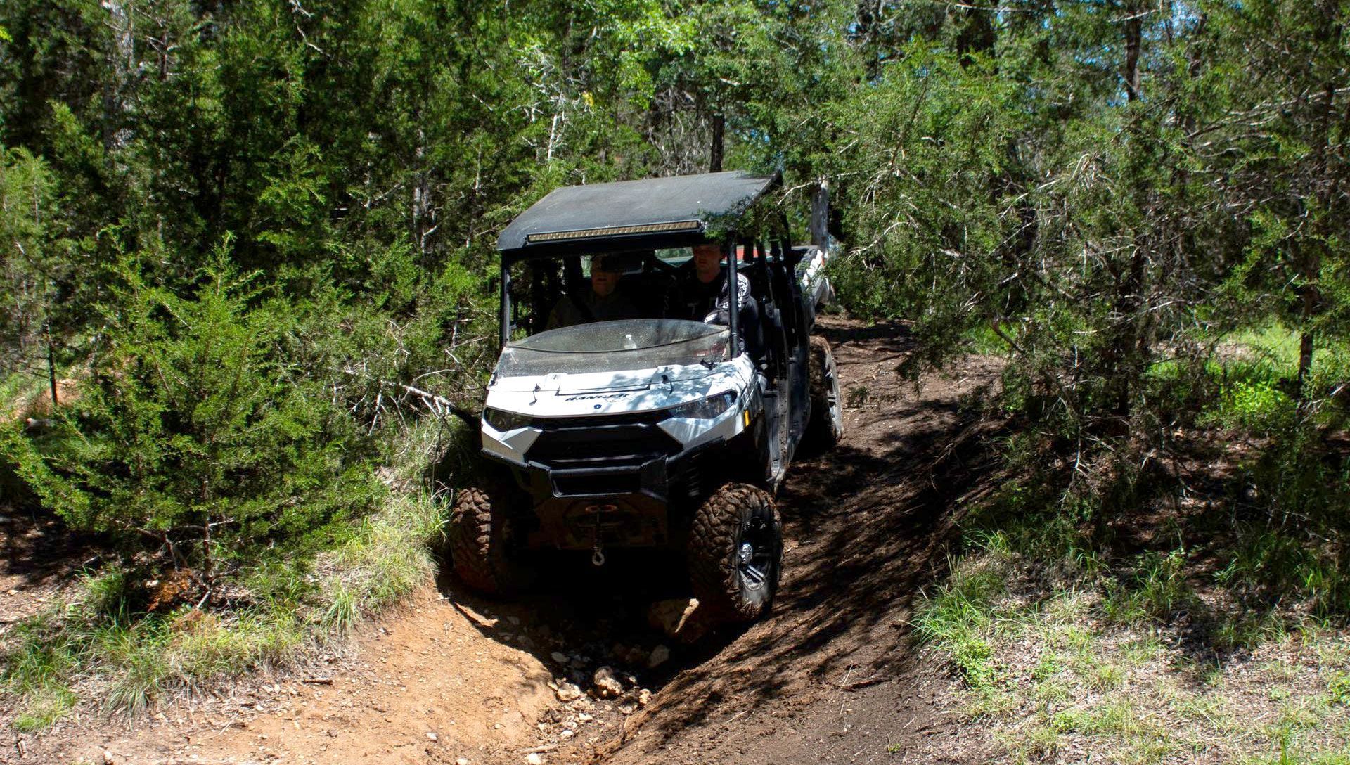Off-road utility vehicle driving through a muddy forest trail