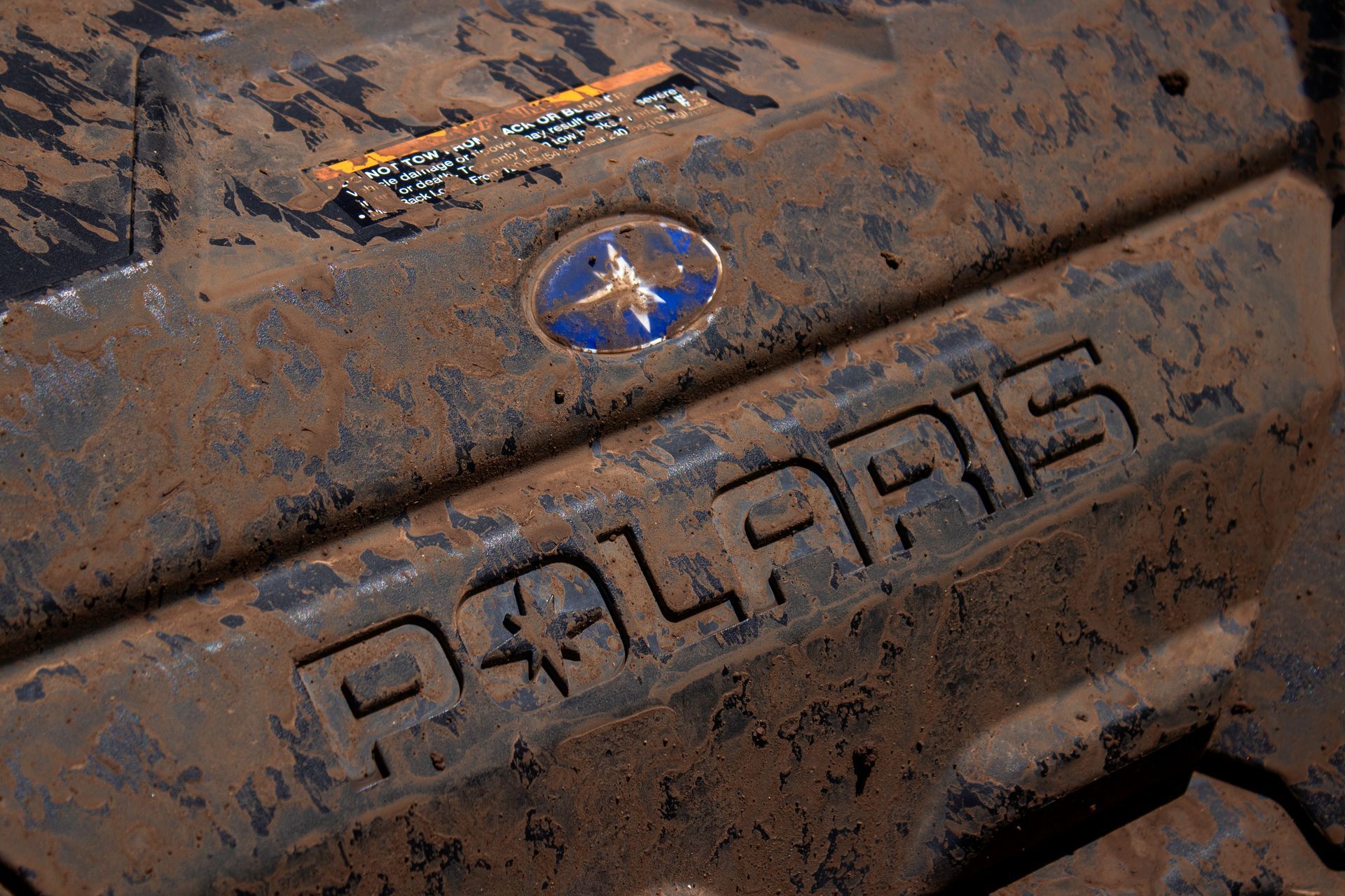 Close-up of a muddy Subaru vehicle body with the logo and badge visible