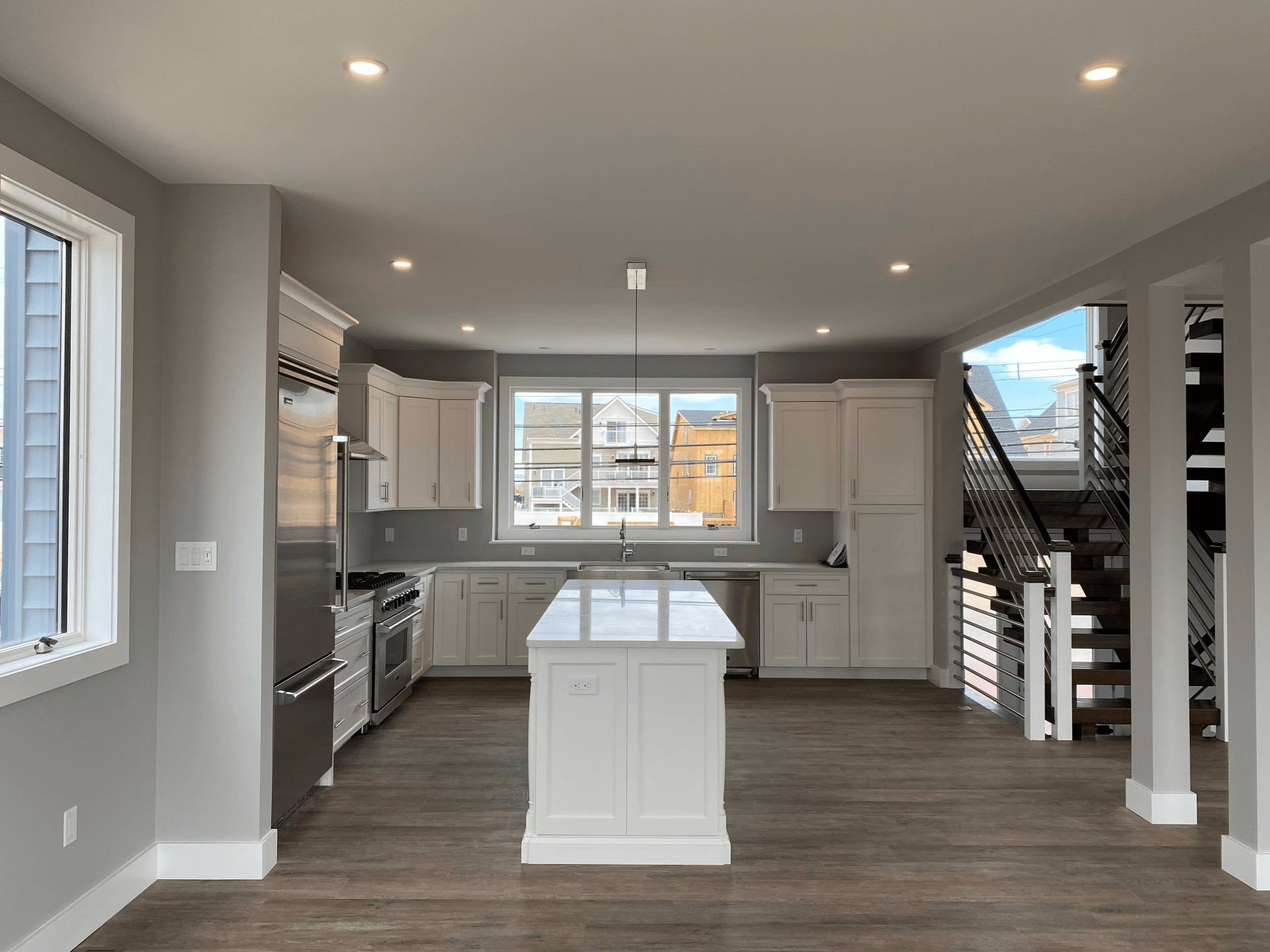 A kitchen with white cabinets , stainless steel appliances , and a large island.
