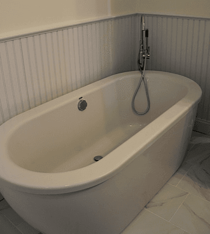 A white bathtub with a shower head in a bathroom.