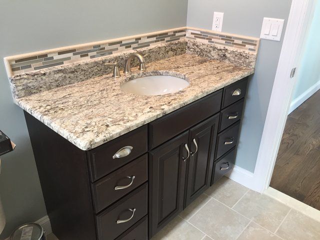 A bathroom vanity with a granite counter top and a sink