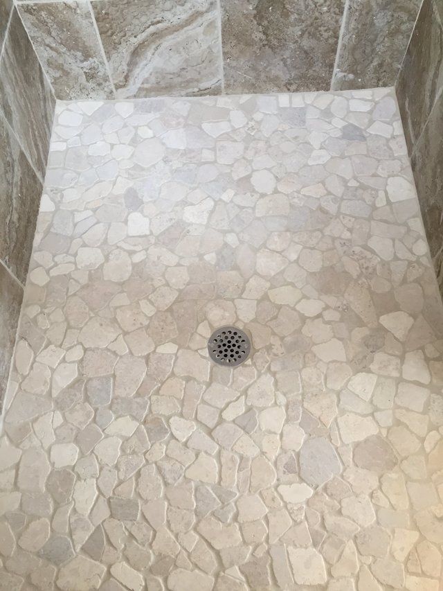 A shower with a tiled floor and a drain.