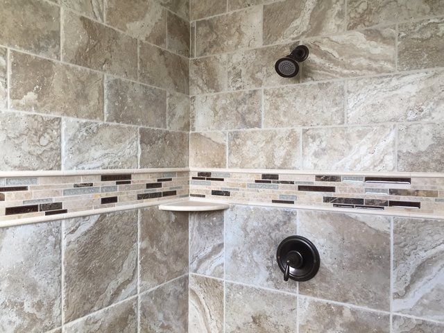 A shower with a corner shelf and a shower head.