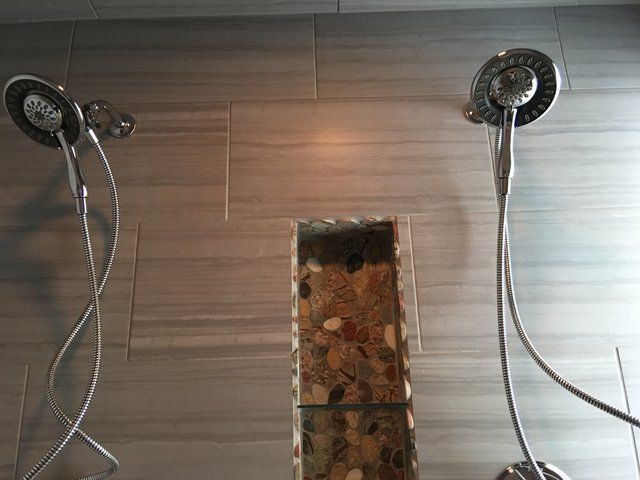 Two shower heads are sitting next to each other in a bathroom.