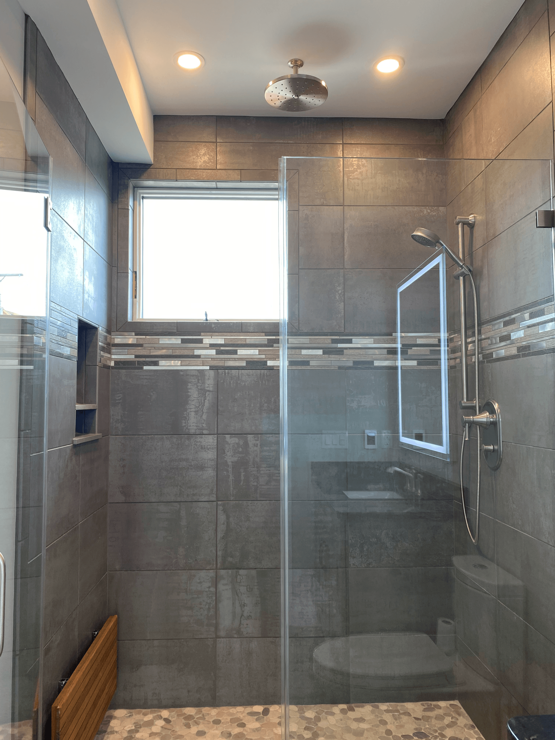 A bathroom with a walk in shower and a window.