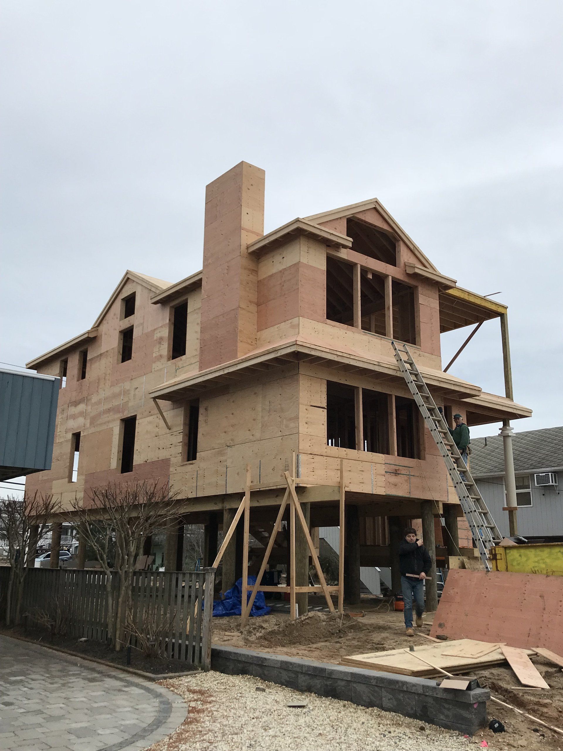 A large house is being built on stilts with a chimney.