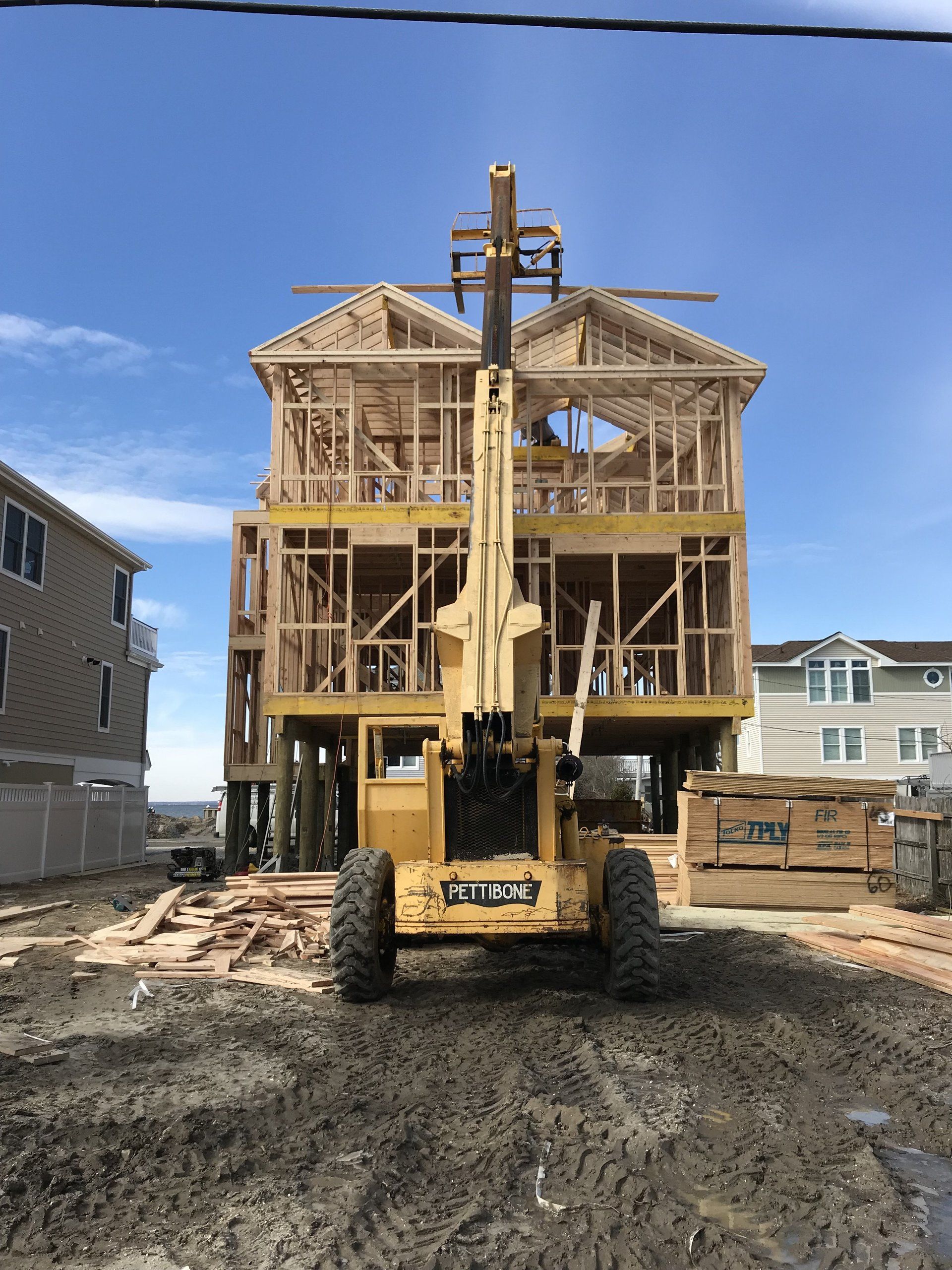 A yellow crane is lifting a house under construction.