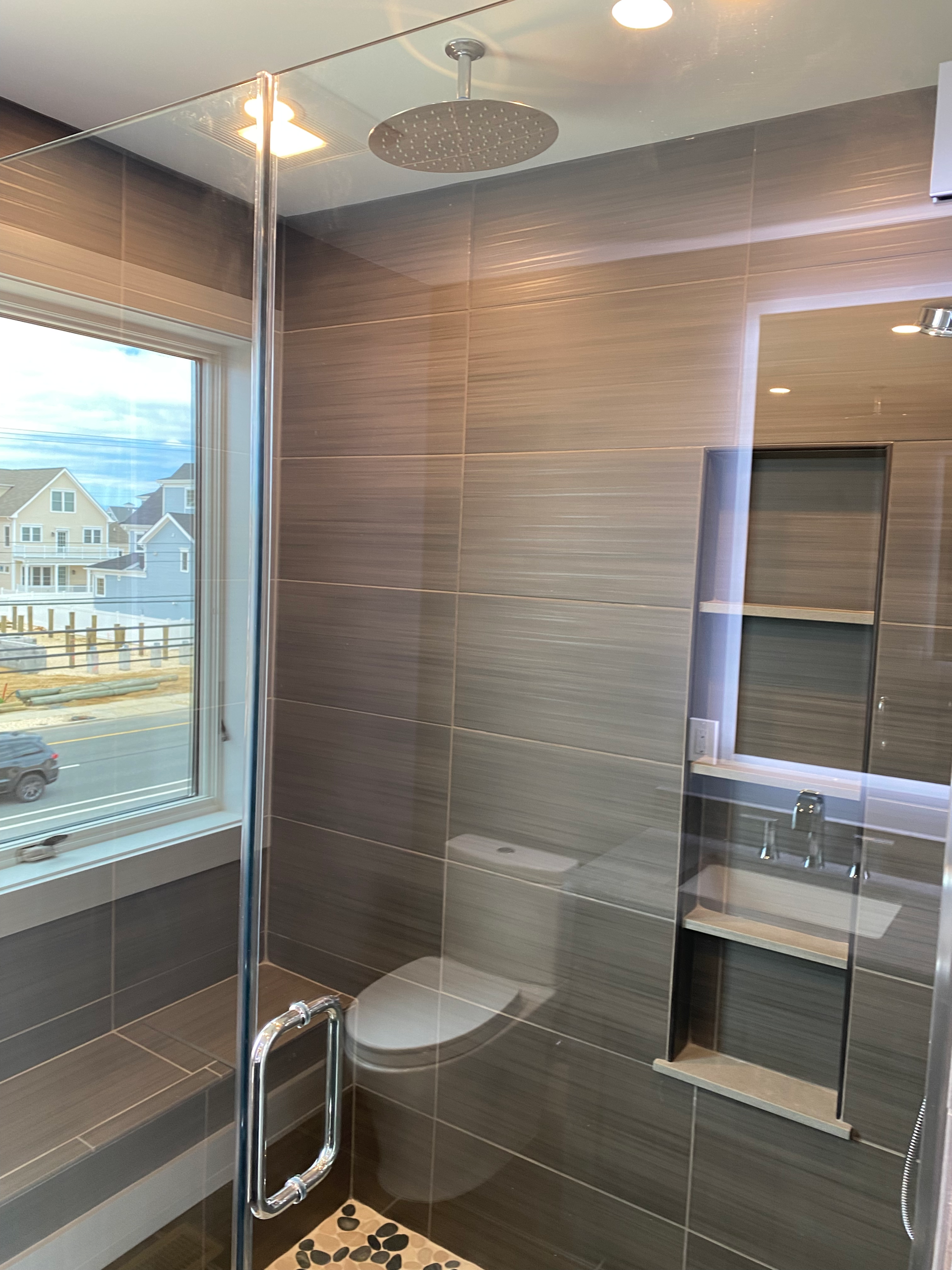 A bathroom with a toilet , sink , shower and mirror.