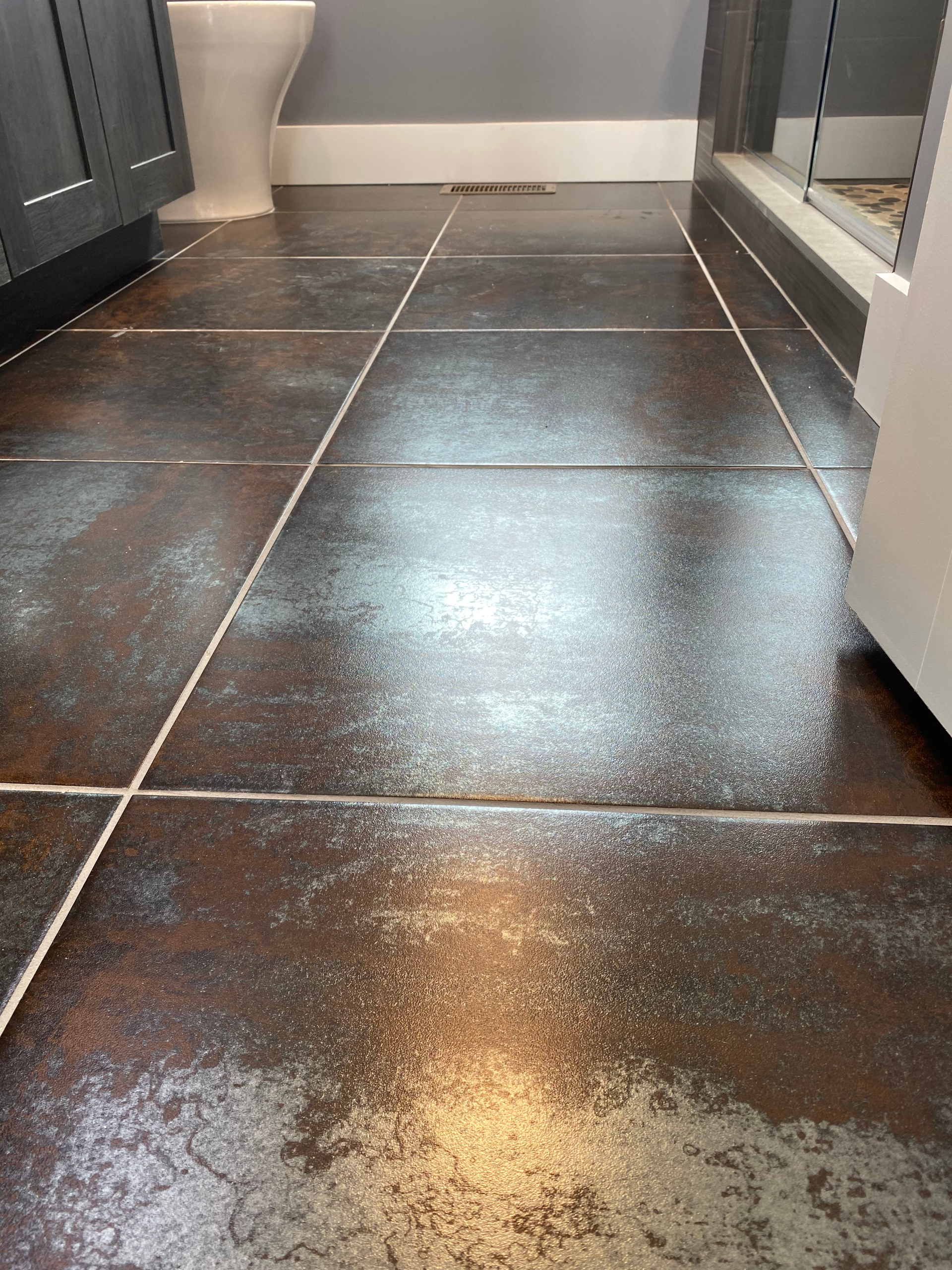 A bathroom with a tiled floor and a toilet