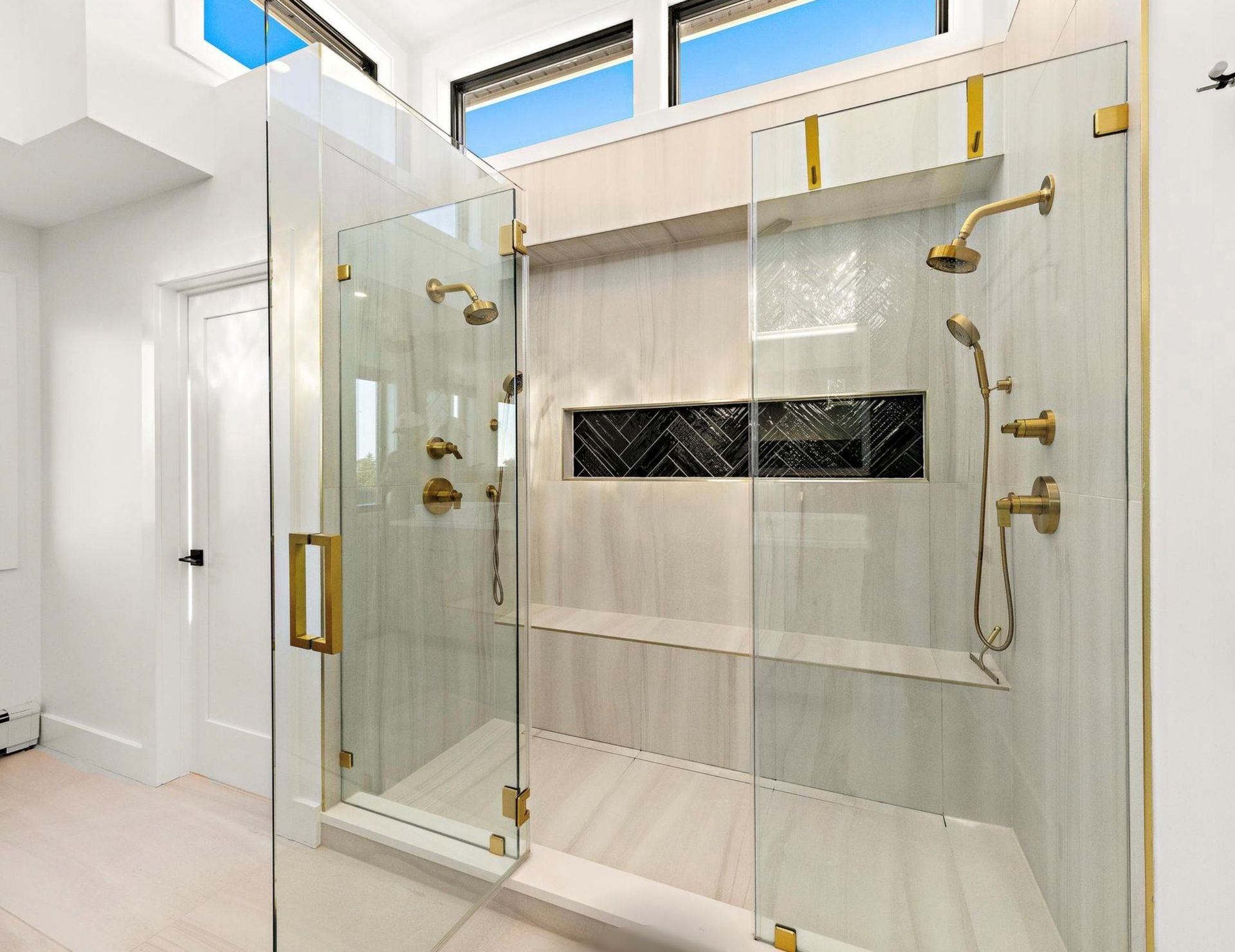 A bathroom with a walk in shower with a glass door.