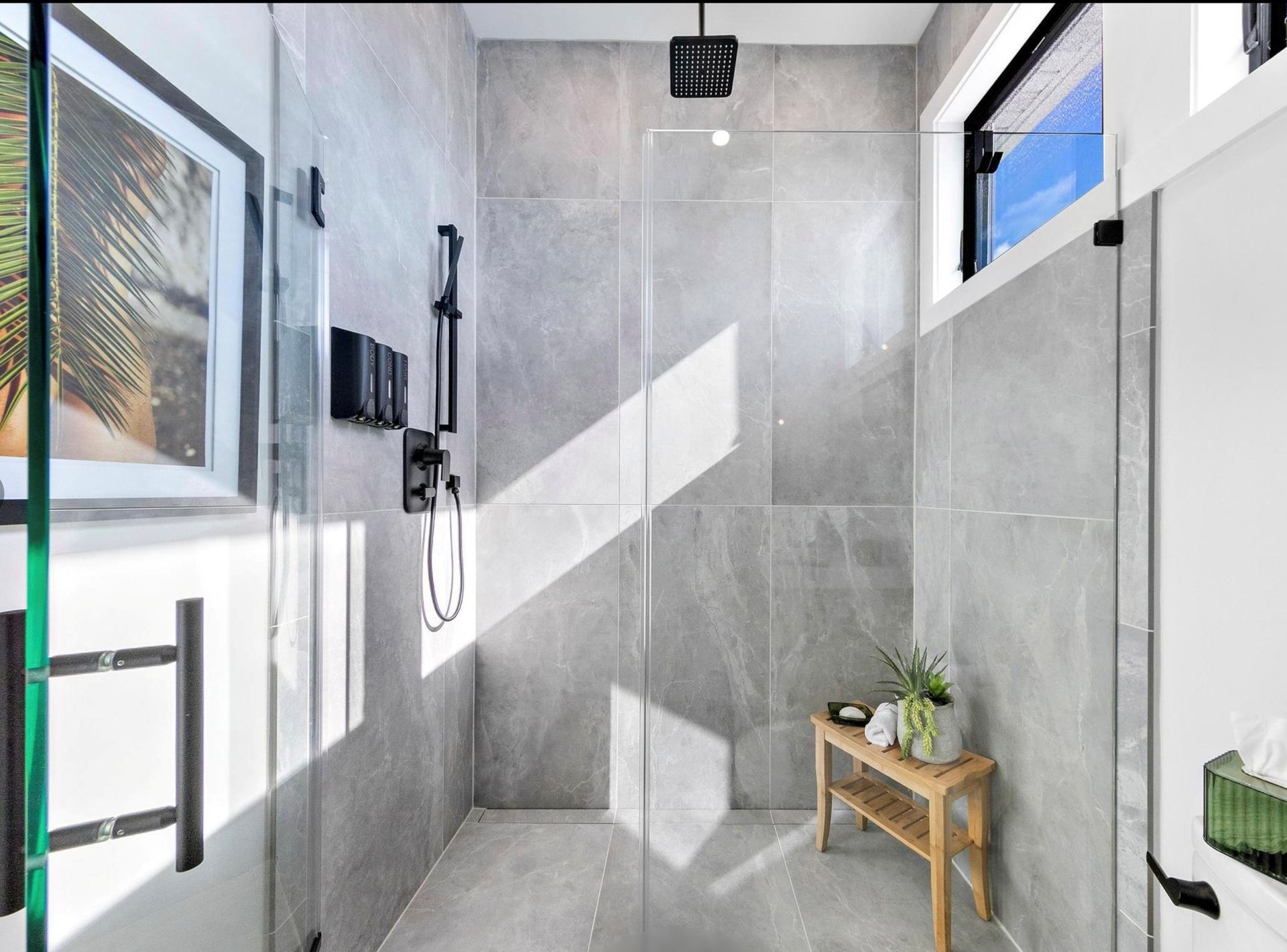 A bathroom with a walk in shower and a wooden bench.