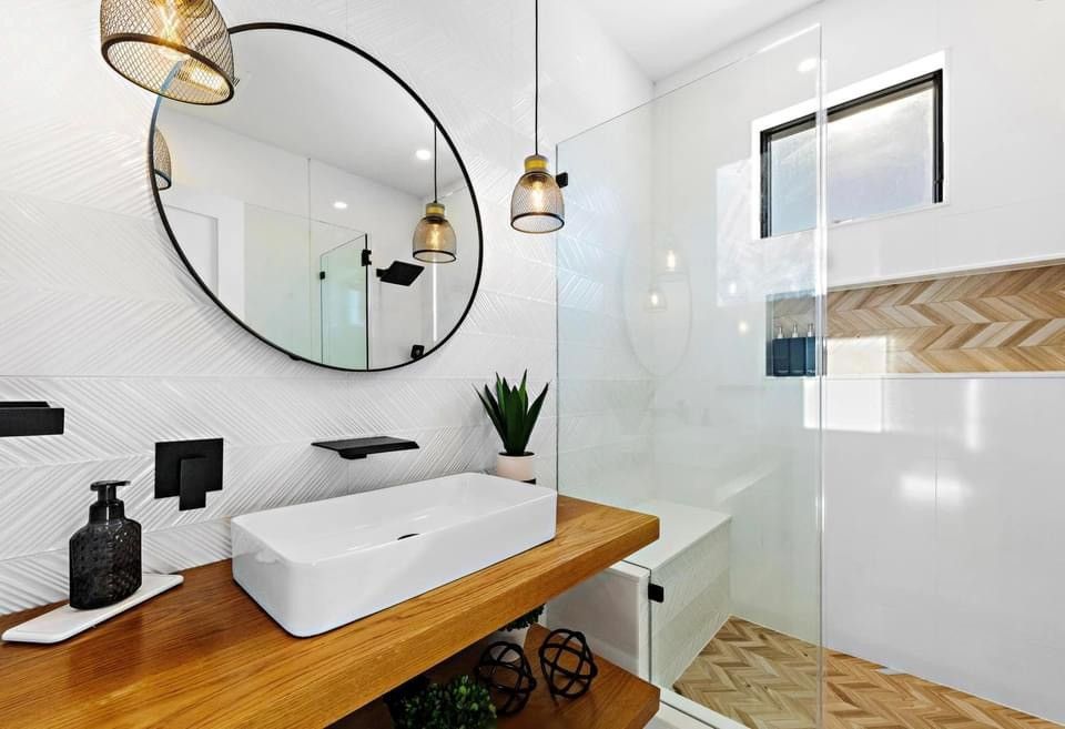 A bathroom with a sink , mirror , and walk in shower.