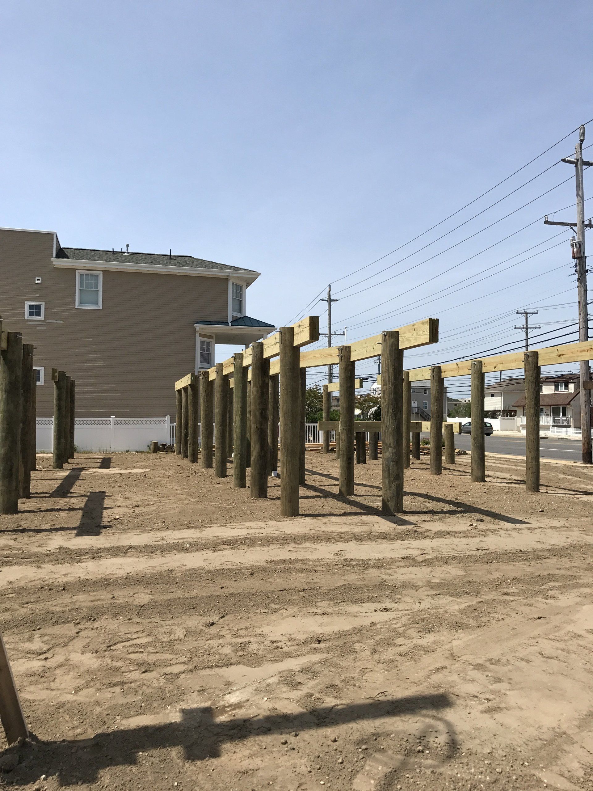 A row of wooden posts are sitting in the dirt in front of a house.
