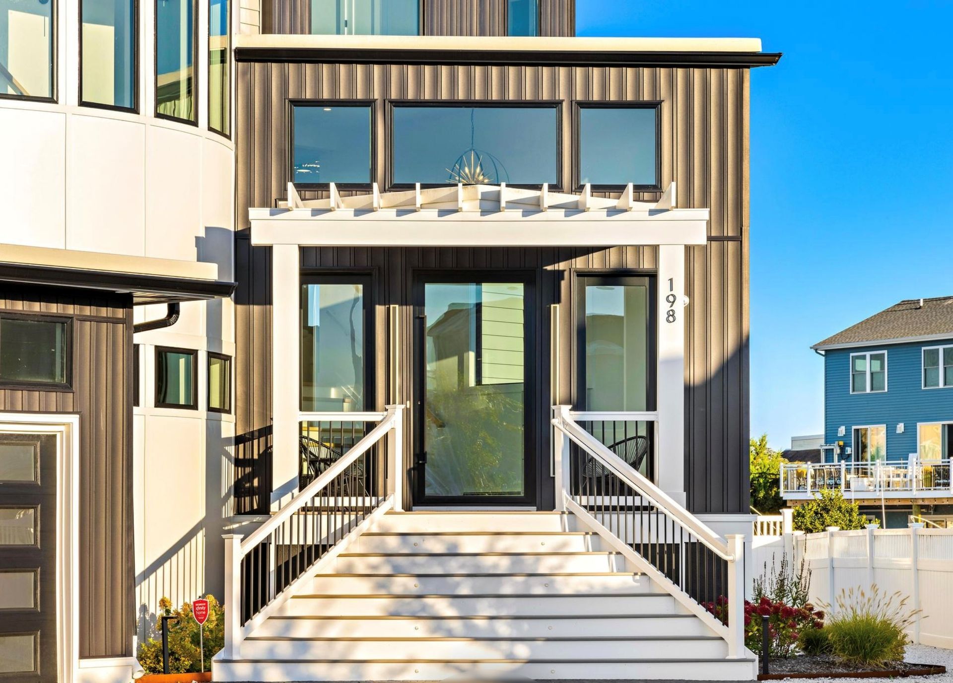 The front of a modern house with stairs leading up to the front door.