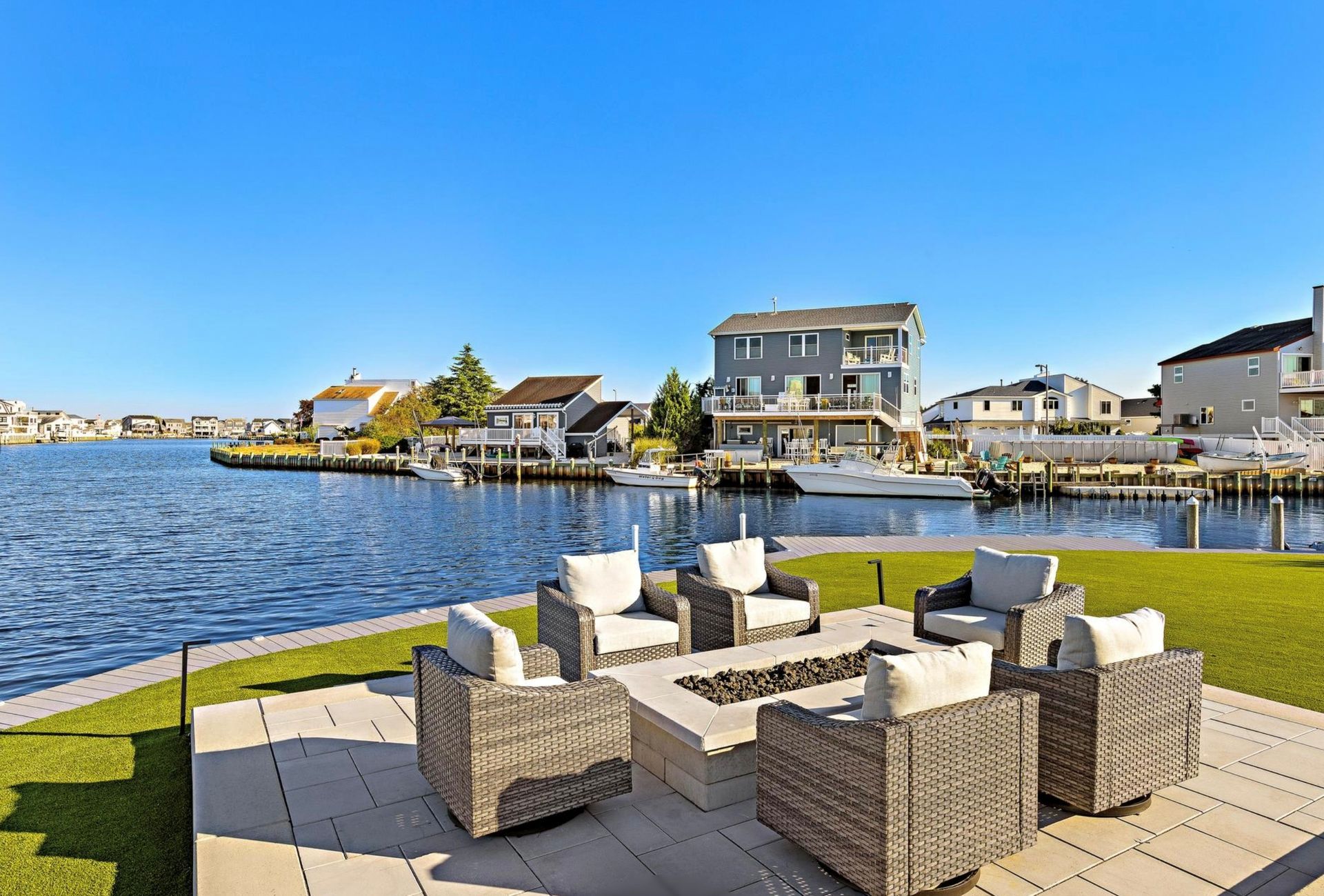 A patio with chairs and a fire pit overlooking a body of water.