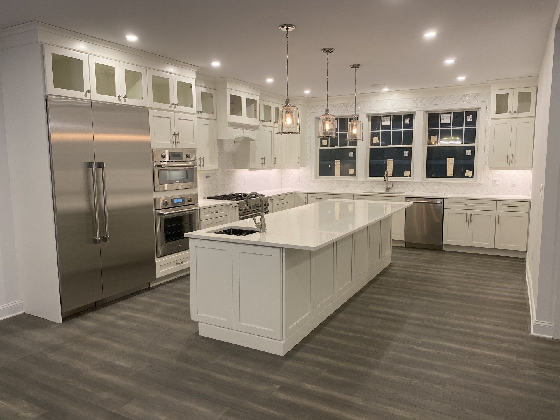 A kitchen with white cabinets , stainless steel appliances , and a large island.