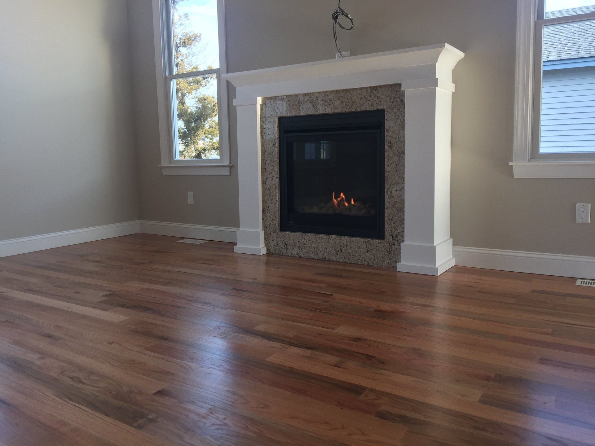An empty living room with hardwood floors and a fireplace.