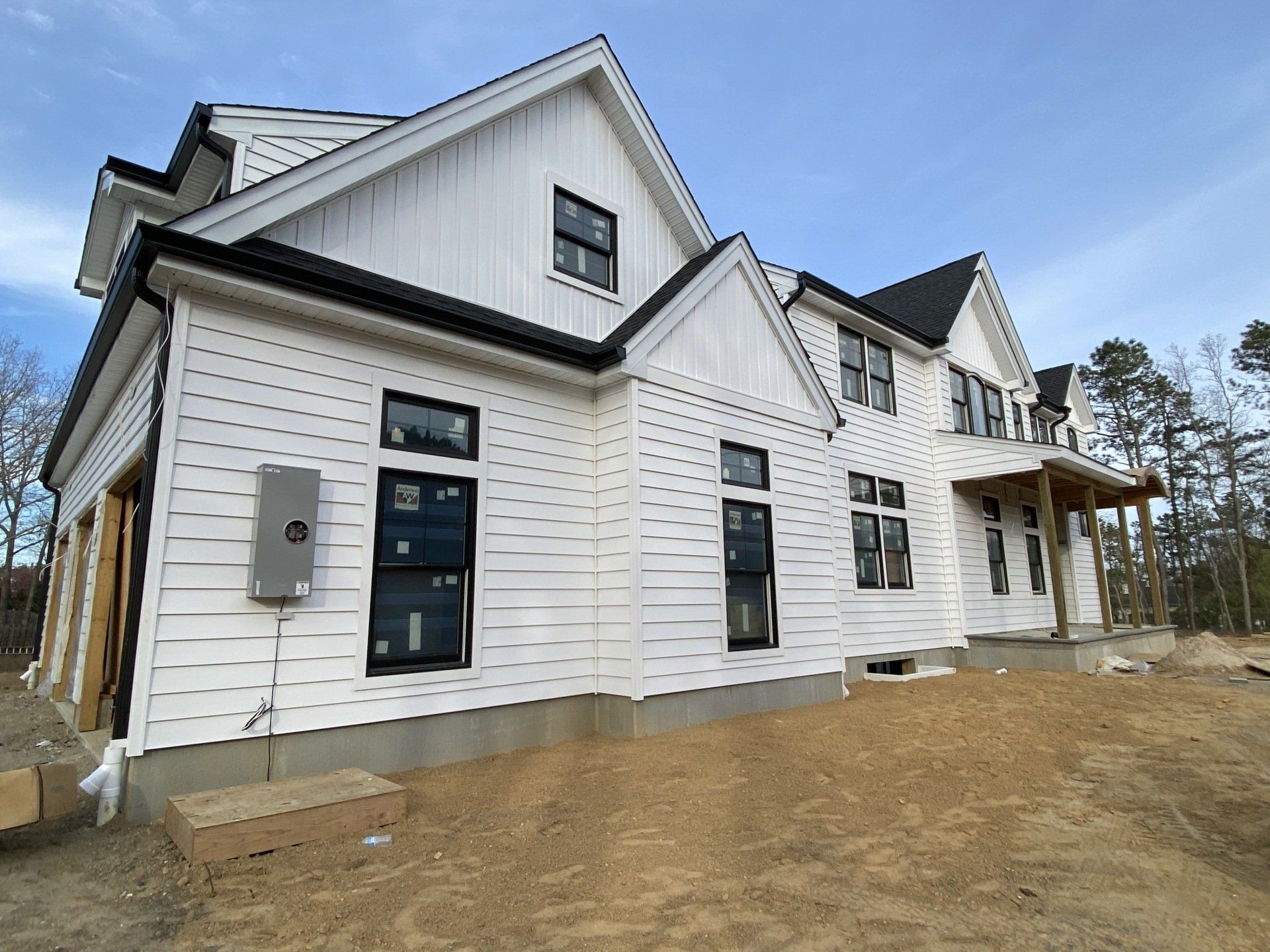 A large white house with black windows is being built.