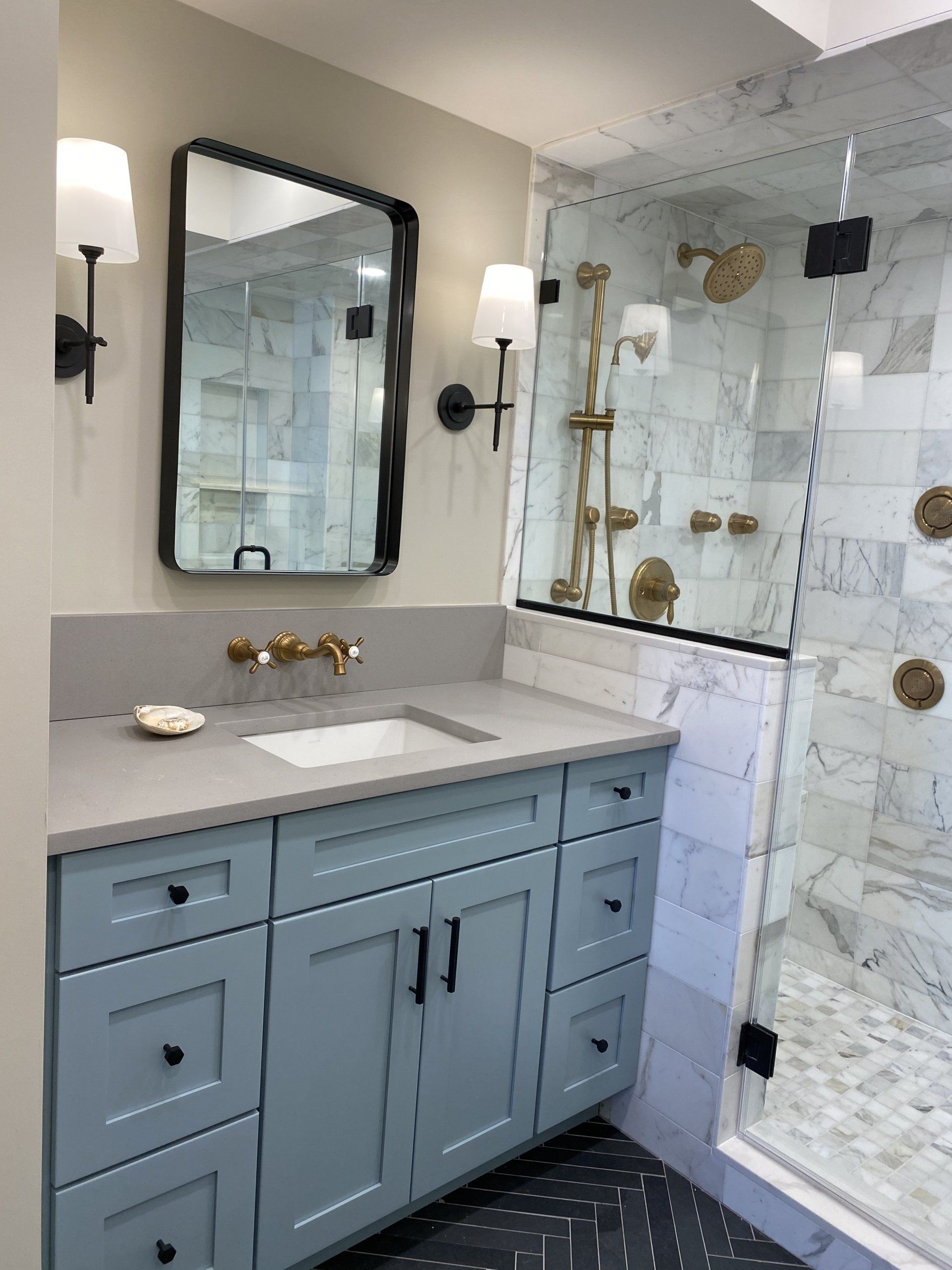 A bathroom with a sink , mirror , and walk in shower.