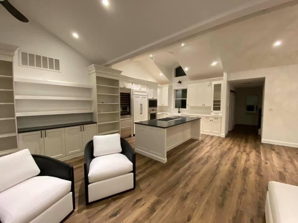 A living room with two chairs , a couch , and a kitchen.