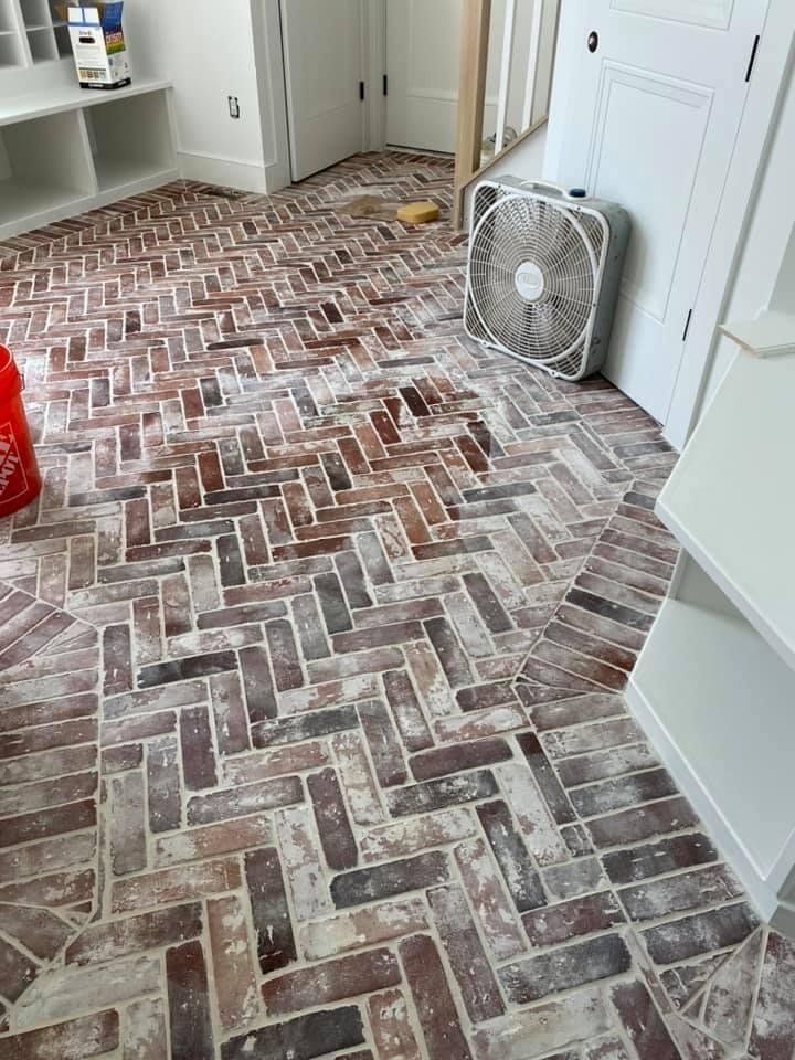 A room with a brick floor and a fan on it.