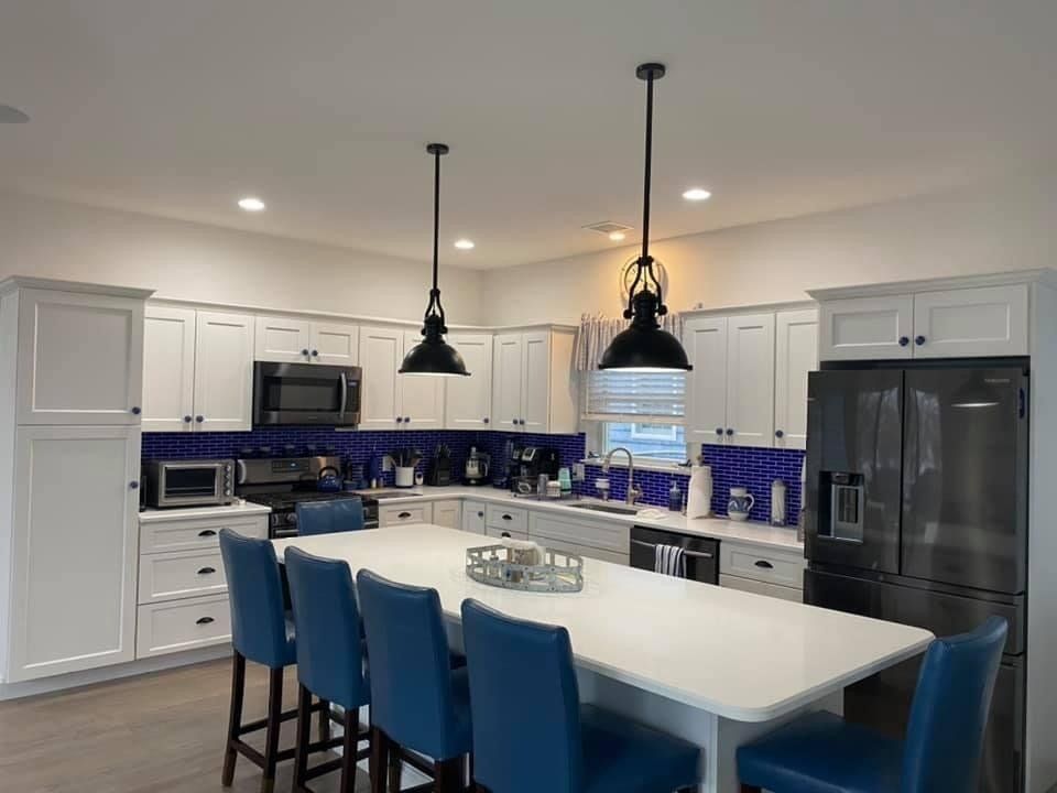 A kitchen with white cabinets and blue chairs and a large island.