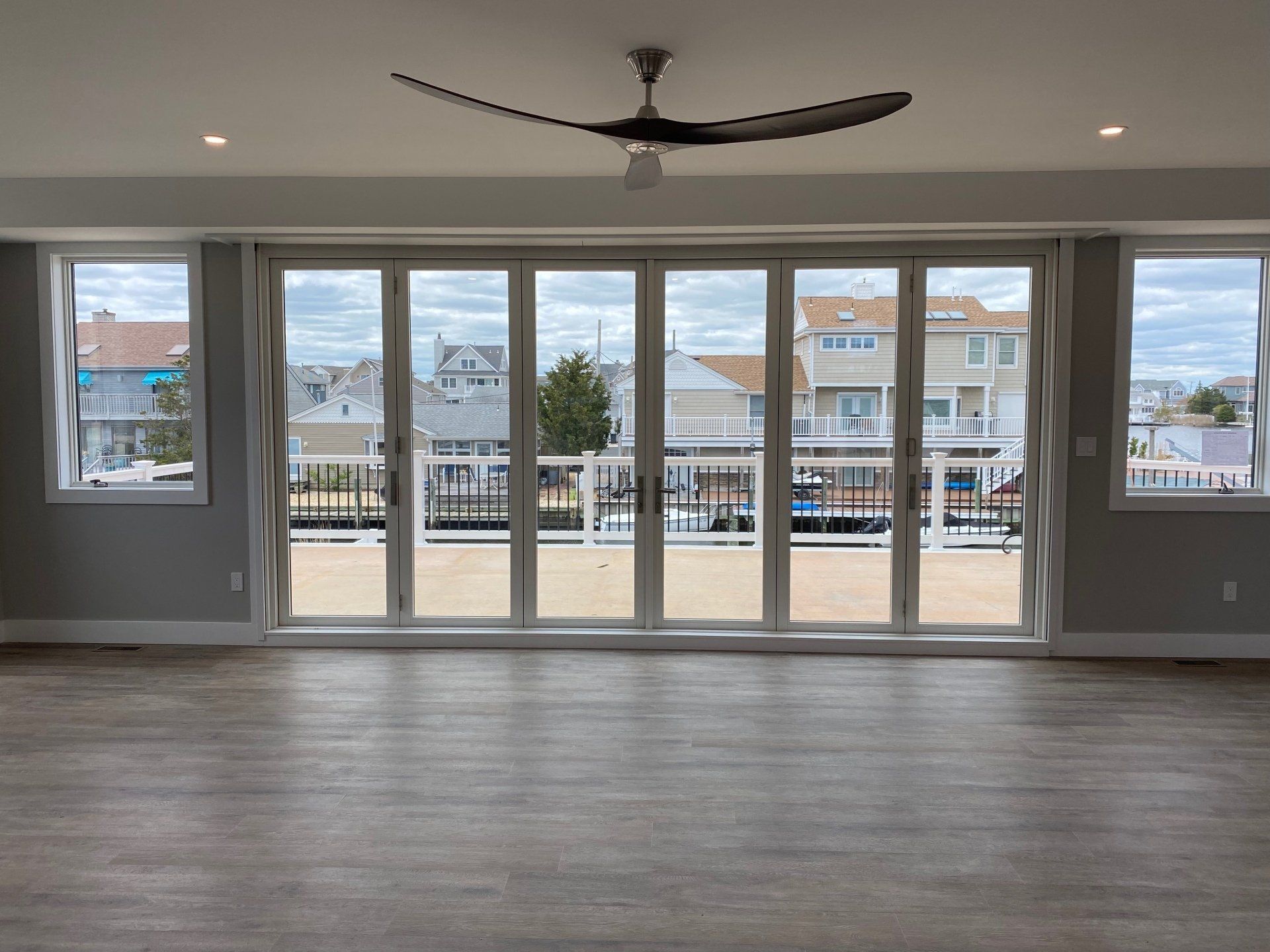 A living room with a lot of windows and a ceiling fan