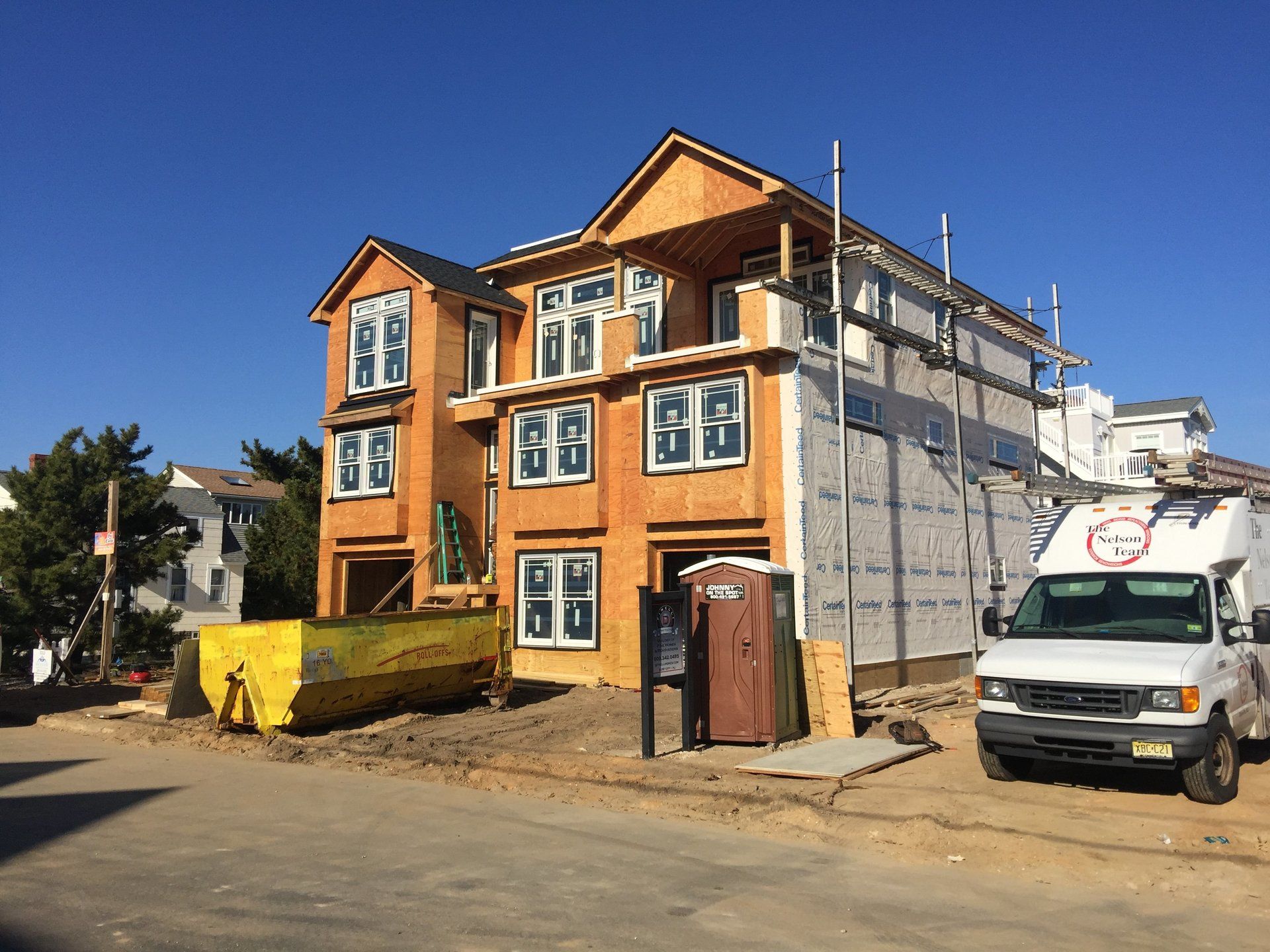 A white van is parked in front of a building under construction.