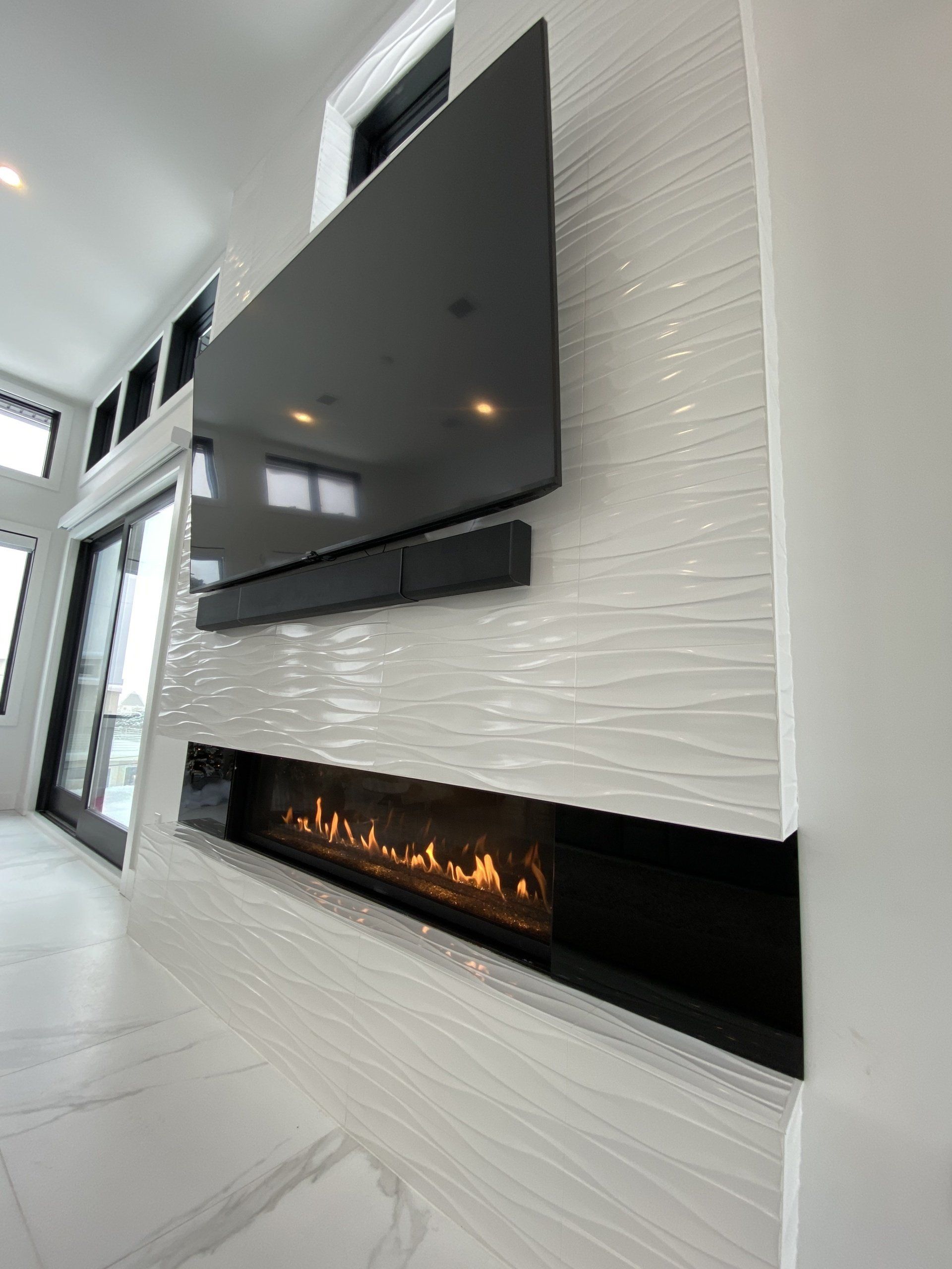 A living room with a fireplace and a flat screen tv on the wall.