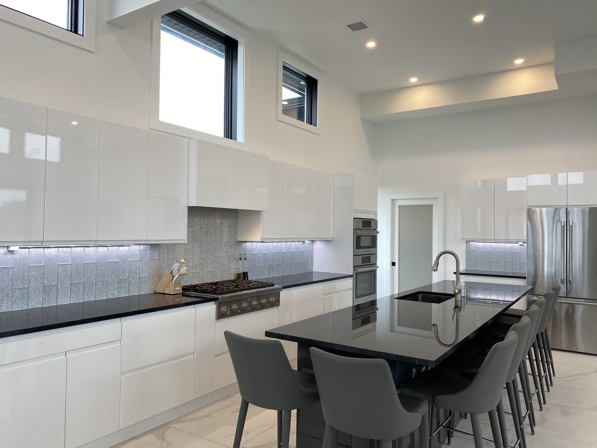 A kitchen with white cabinets and black counter tops and a large island in the middle.