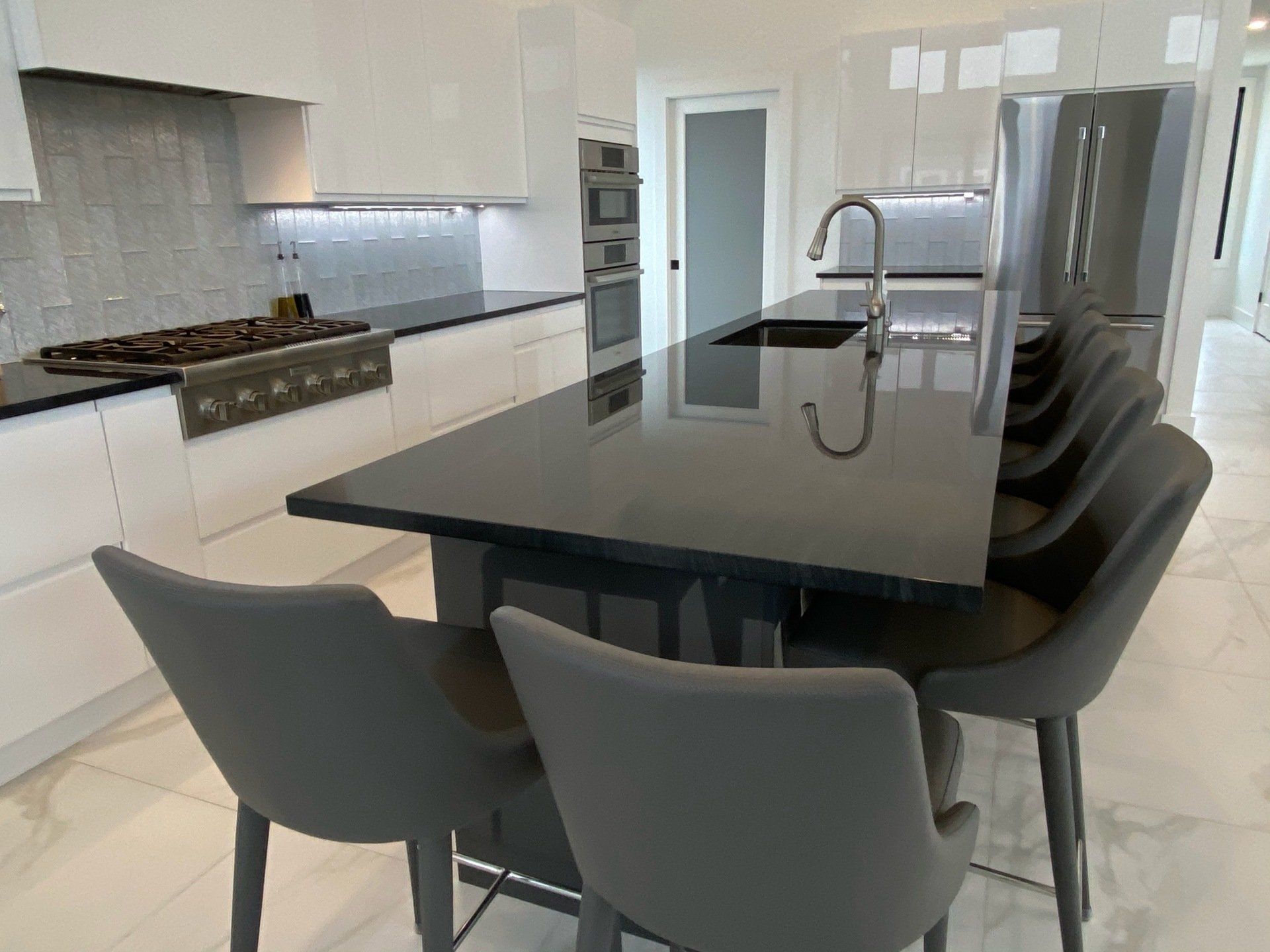 A kitchen with a large island , stove , sink and chairs.