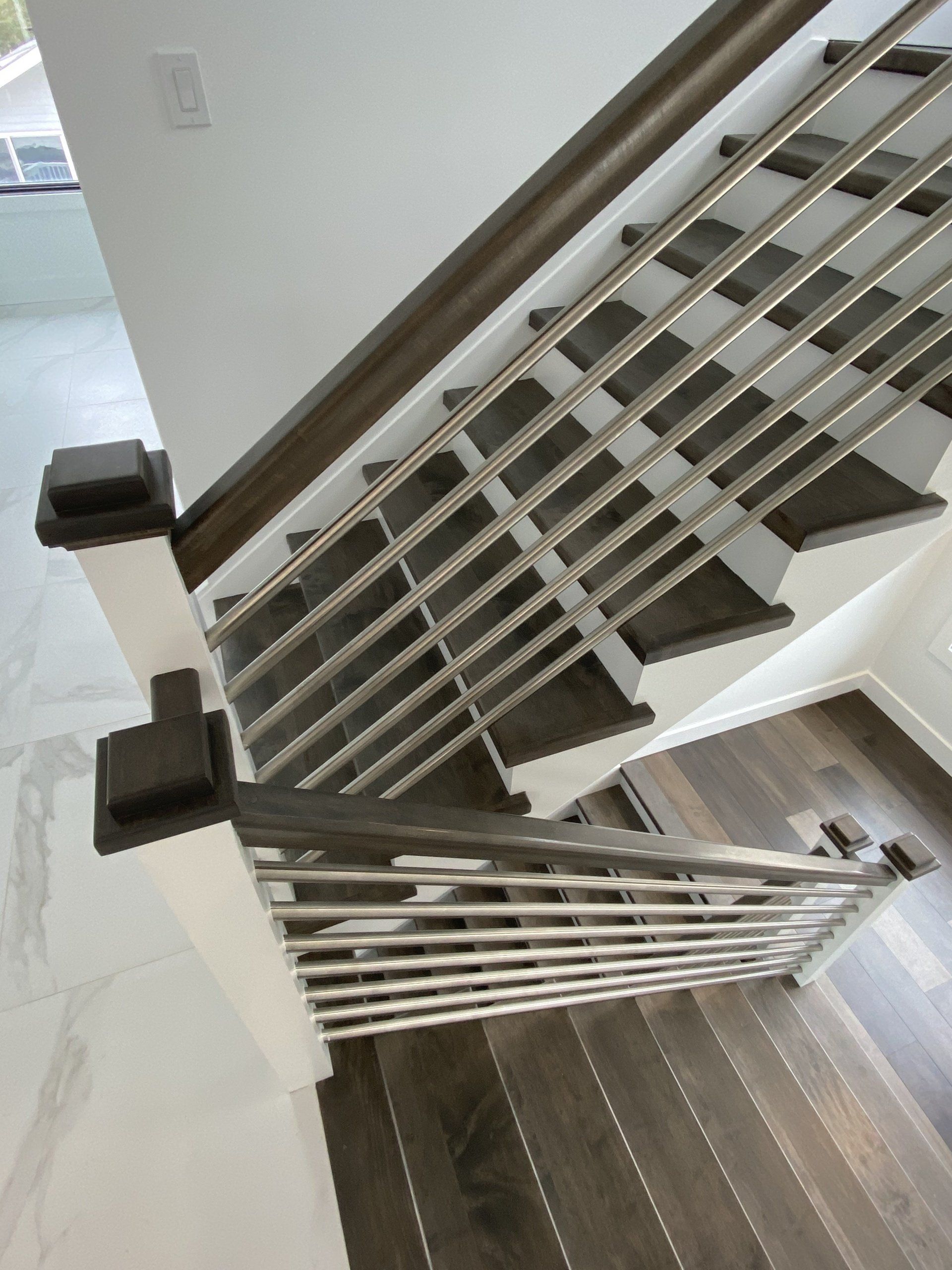 A staircase with a stainless steel railing and wooden steps.