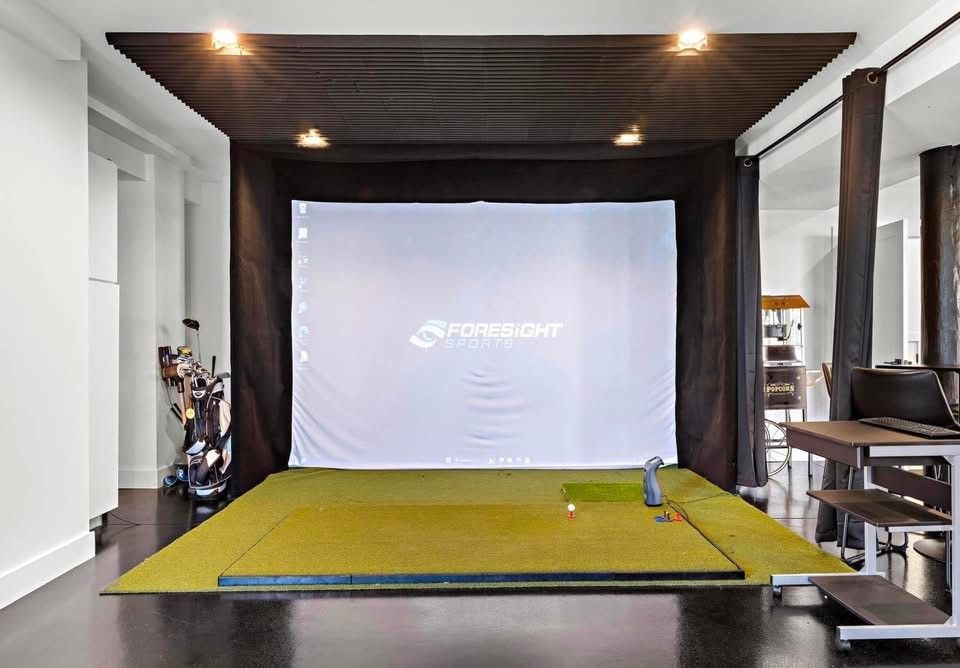 There is a golf simulator in the middle of the room.