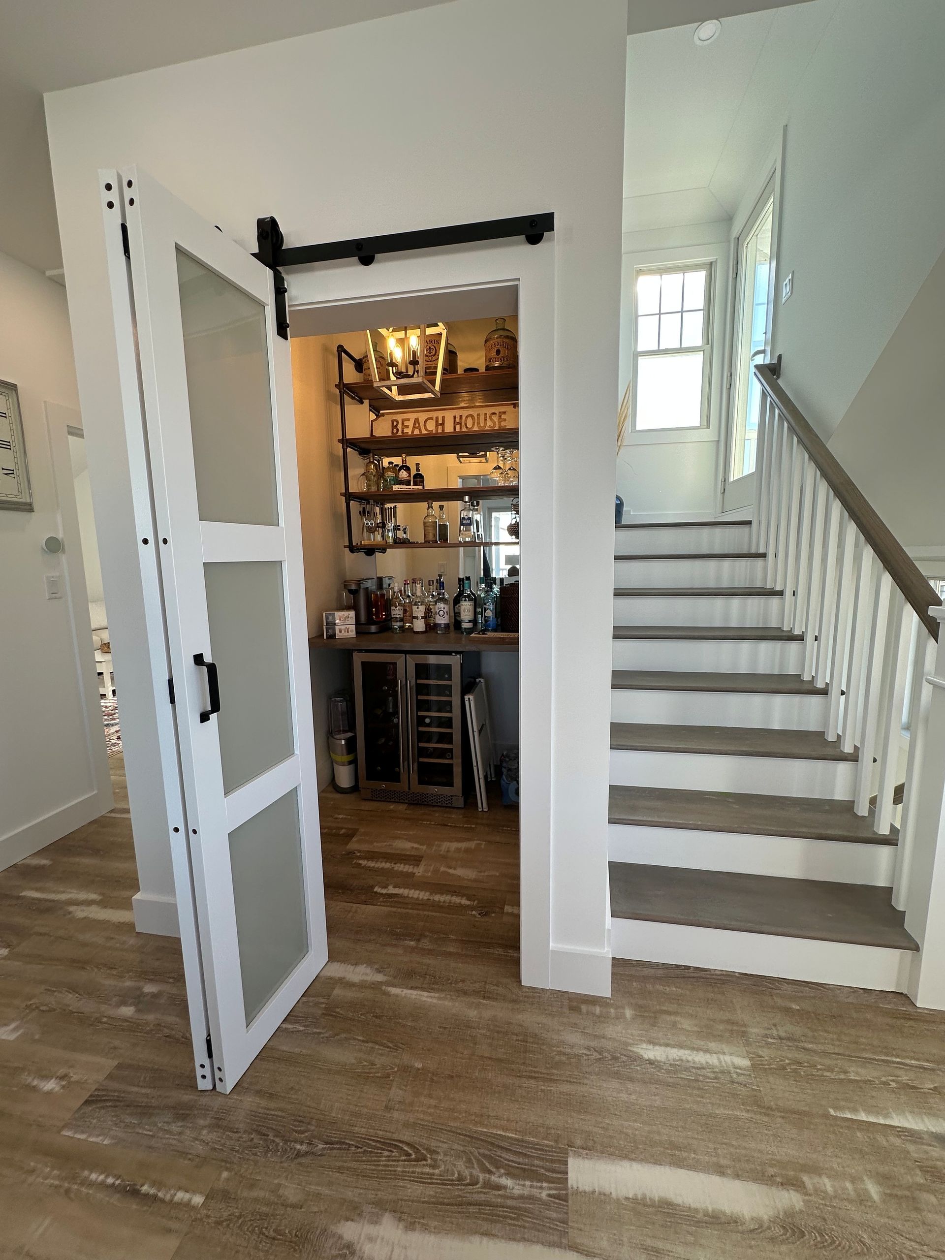 A hallway with stairs leading up to a bar and a sliding barn door.