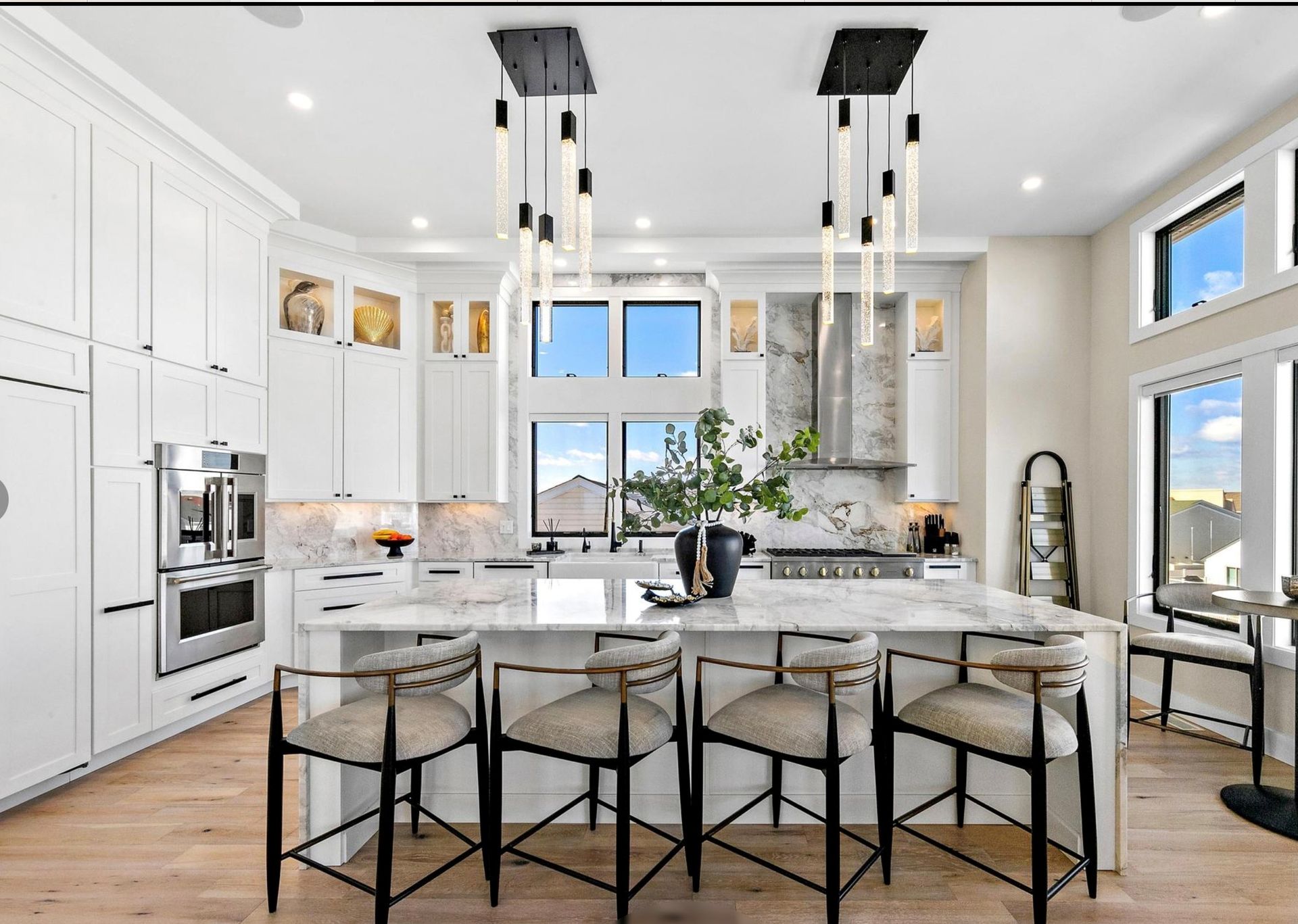 A kitchen with white cabinets , stainless steel appliances , and a large island.