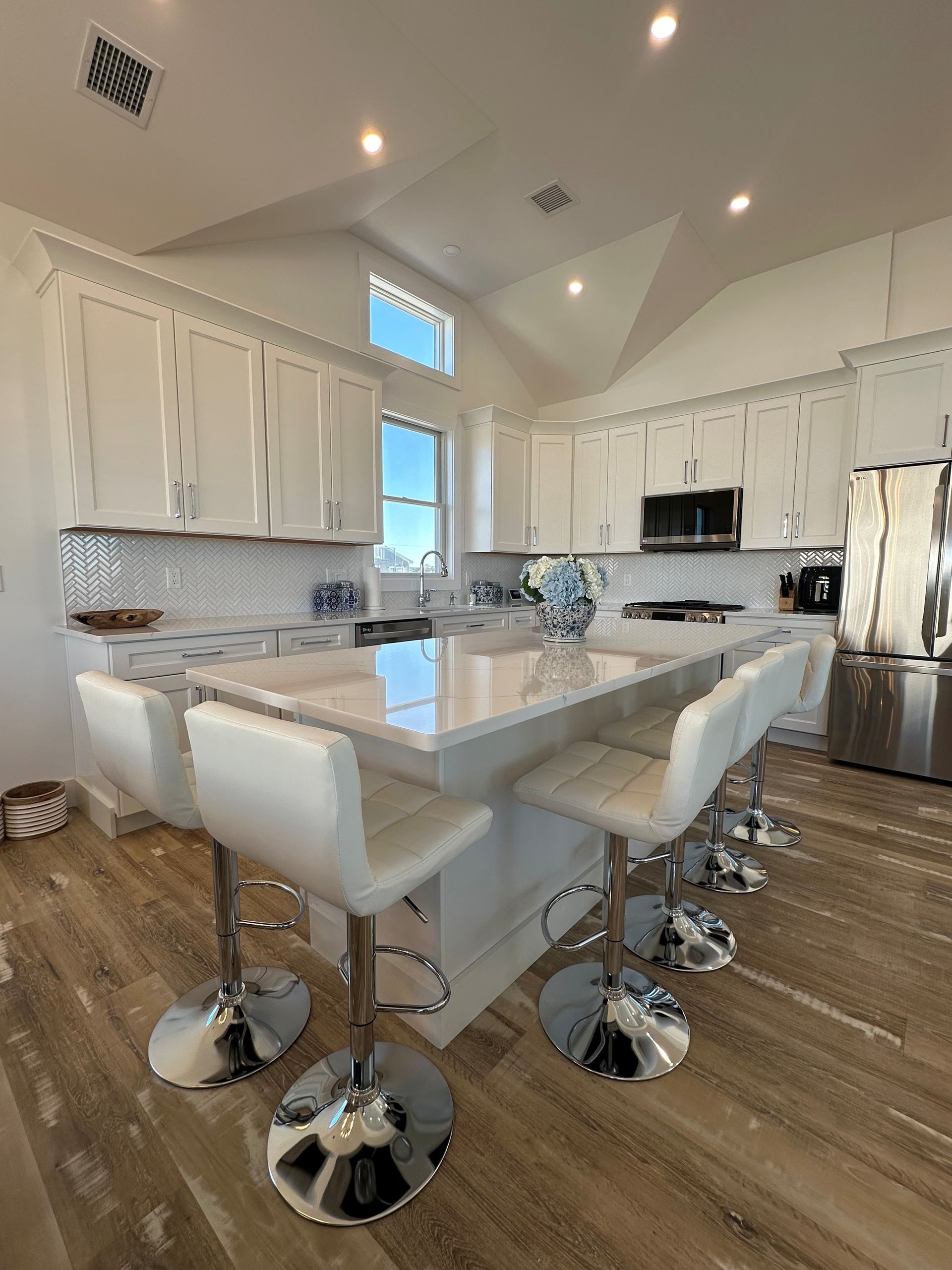 A kitchen with white cabinets and stainless steel appliances and a large island.