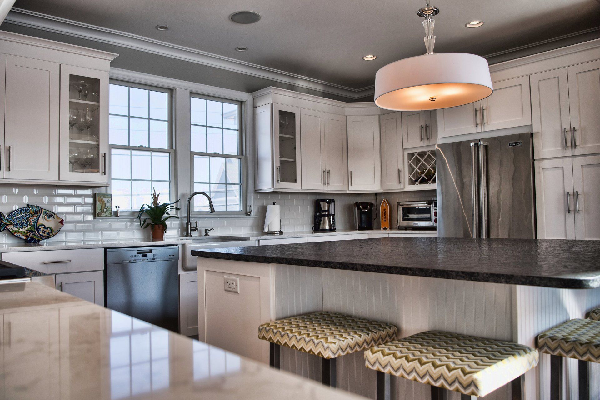 A kitchen with white cabinets and black counter tops