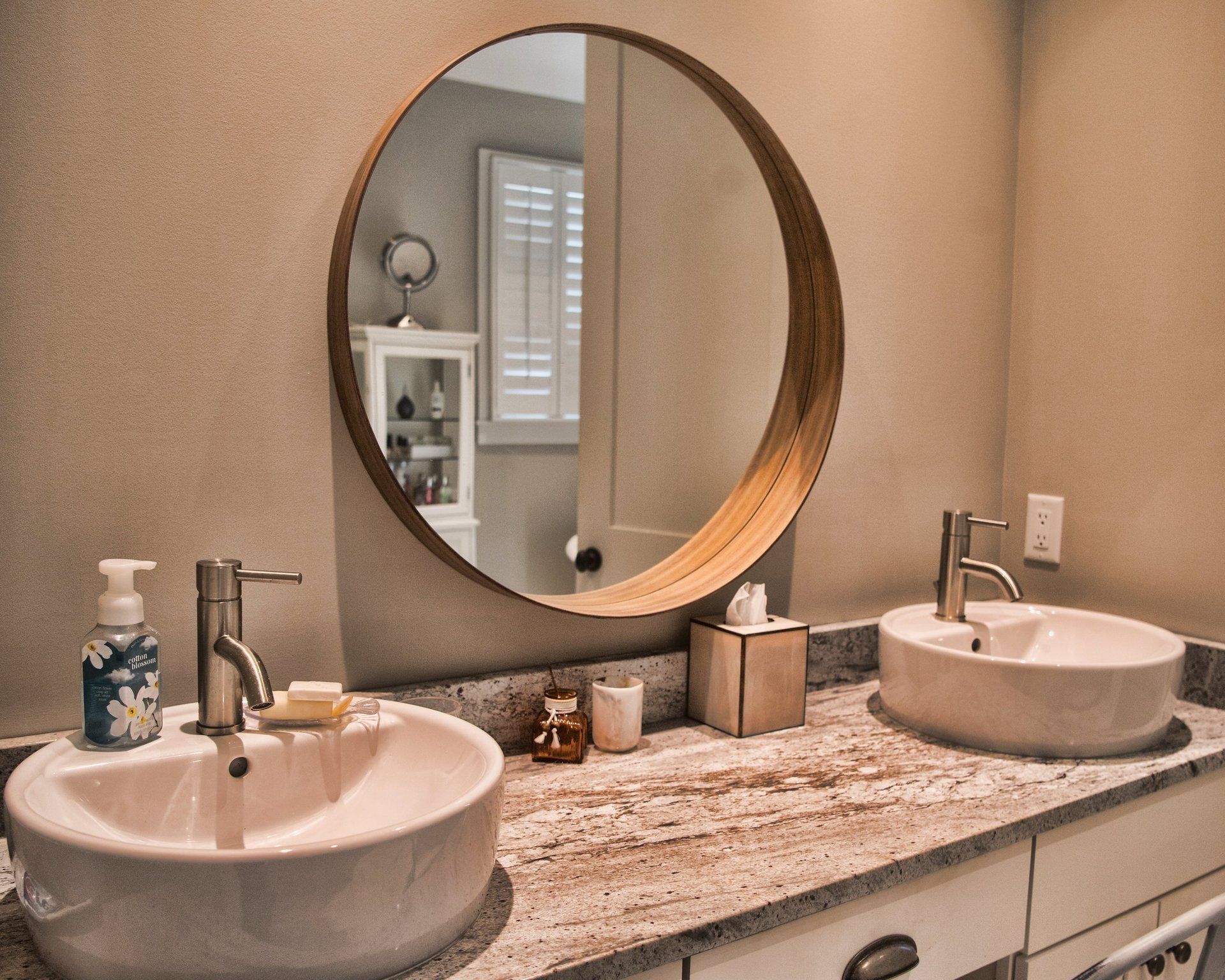 A bathroom with two sinks and a round mirror.
