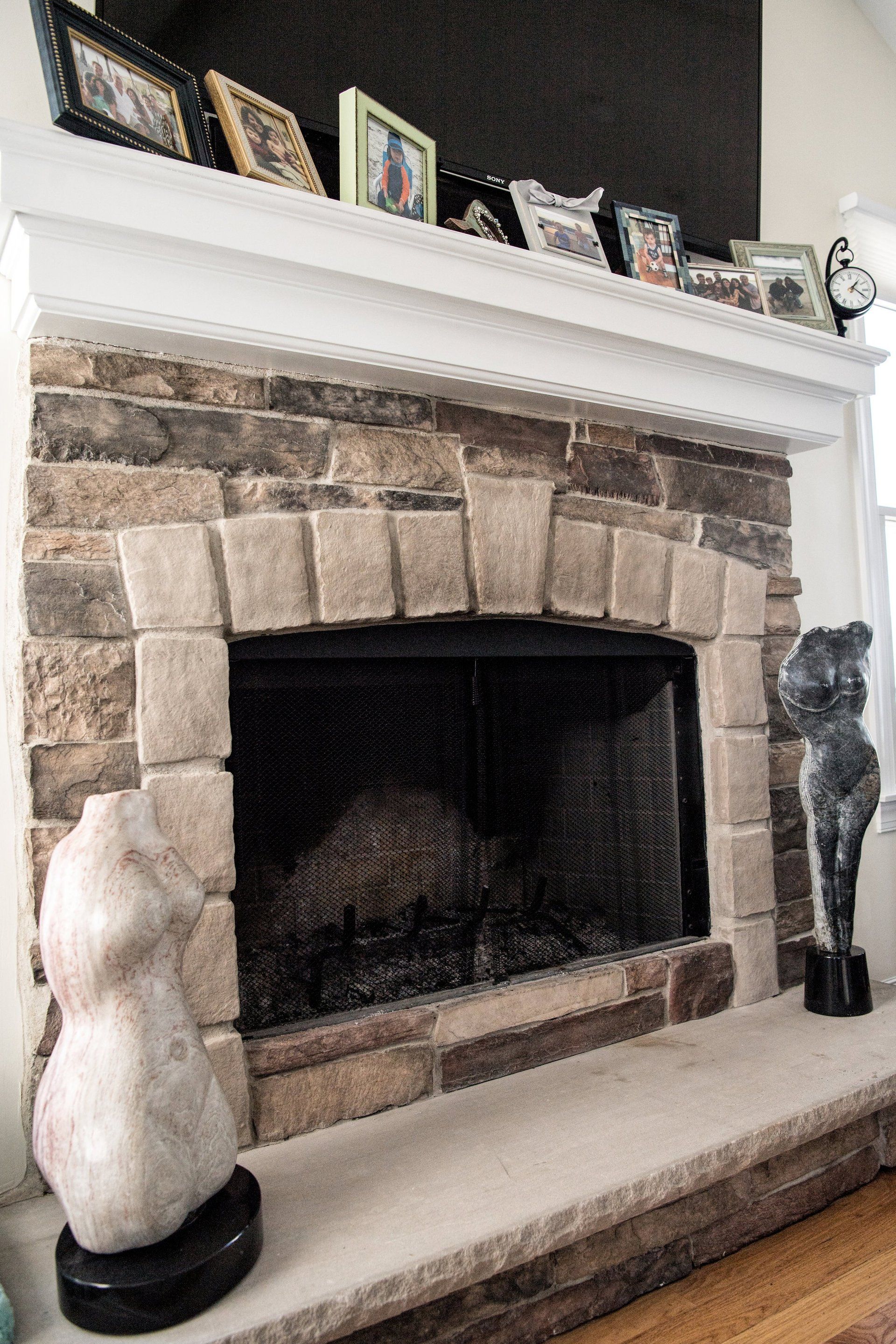 A fireplace in a living room with pictures on the mantle.