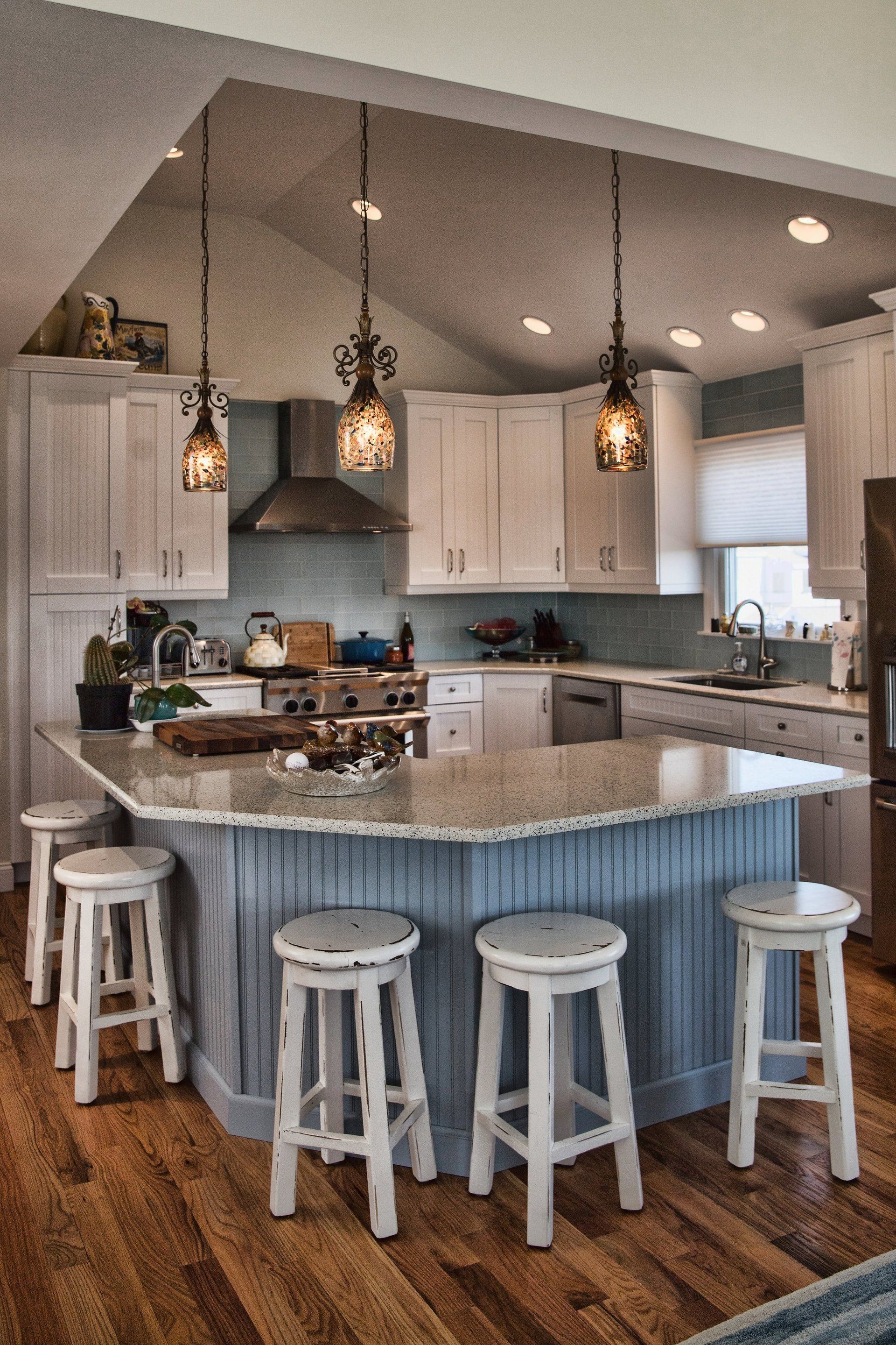 A kitchen with a blue island and white stools