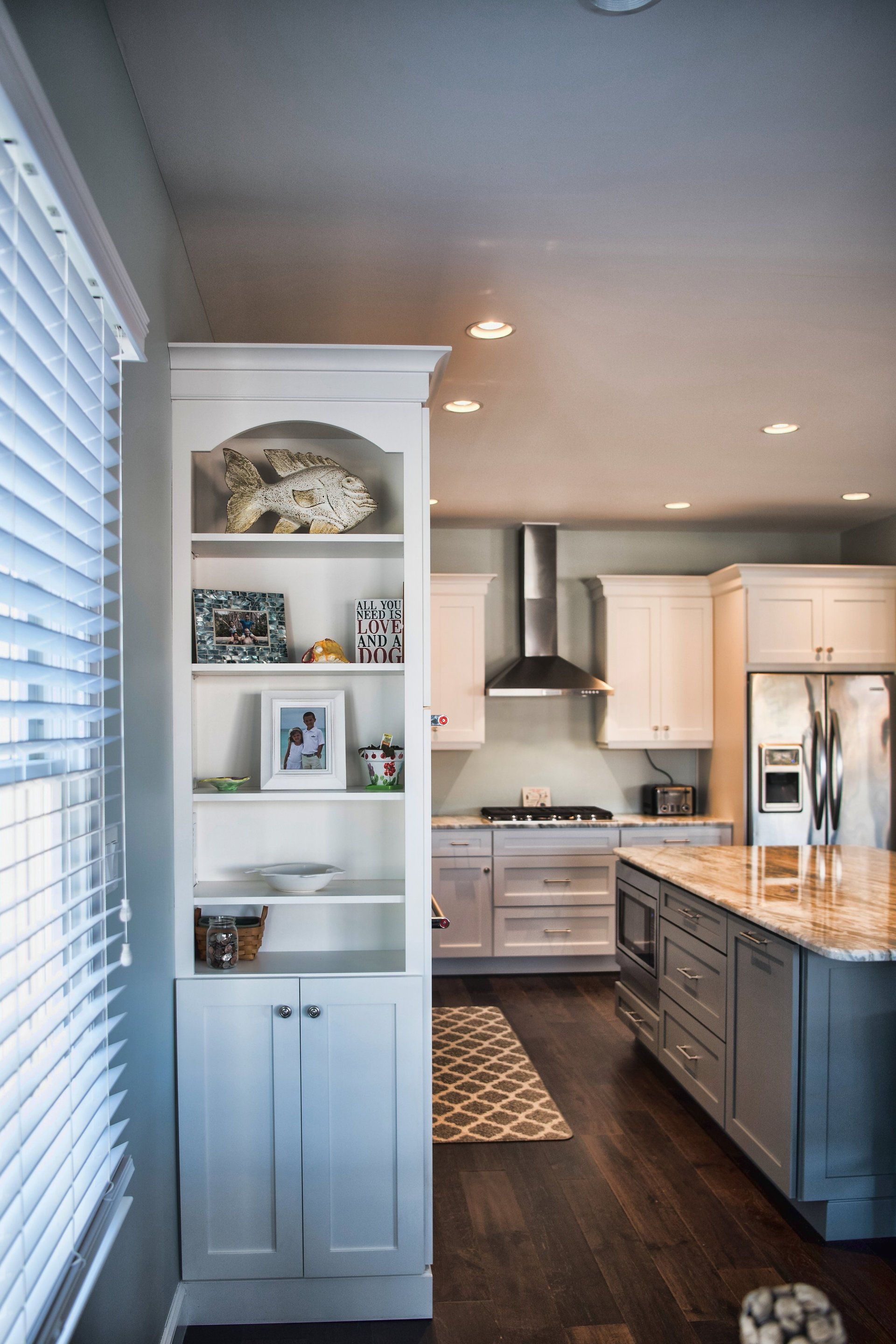 A kitchen with white cabinets , a stove , a refrigerator , and a window.