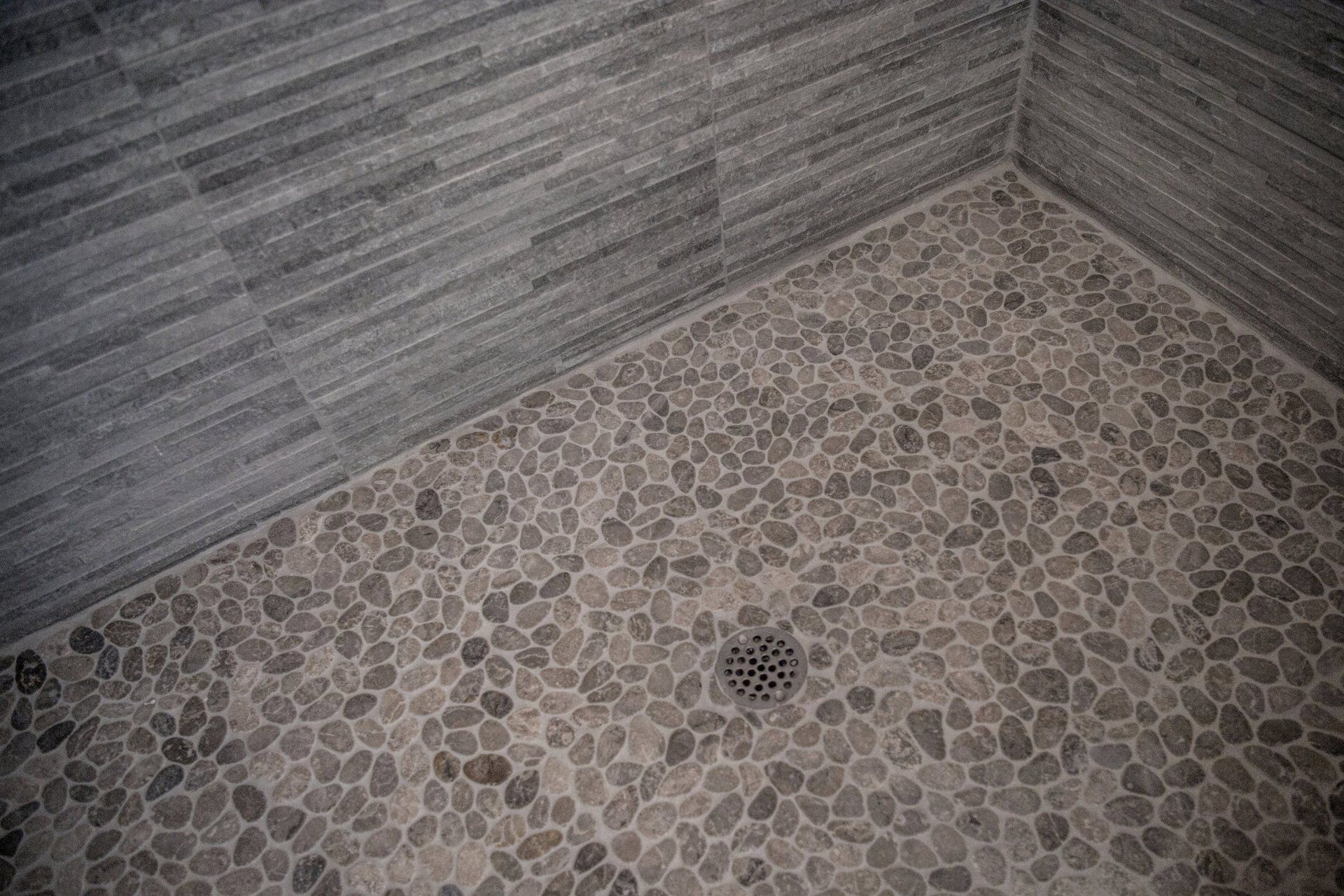 A close up of a shower floor with a drain.